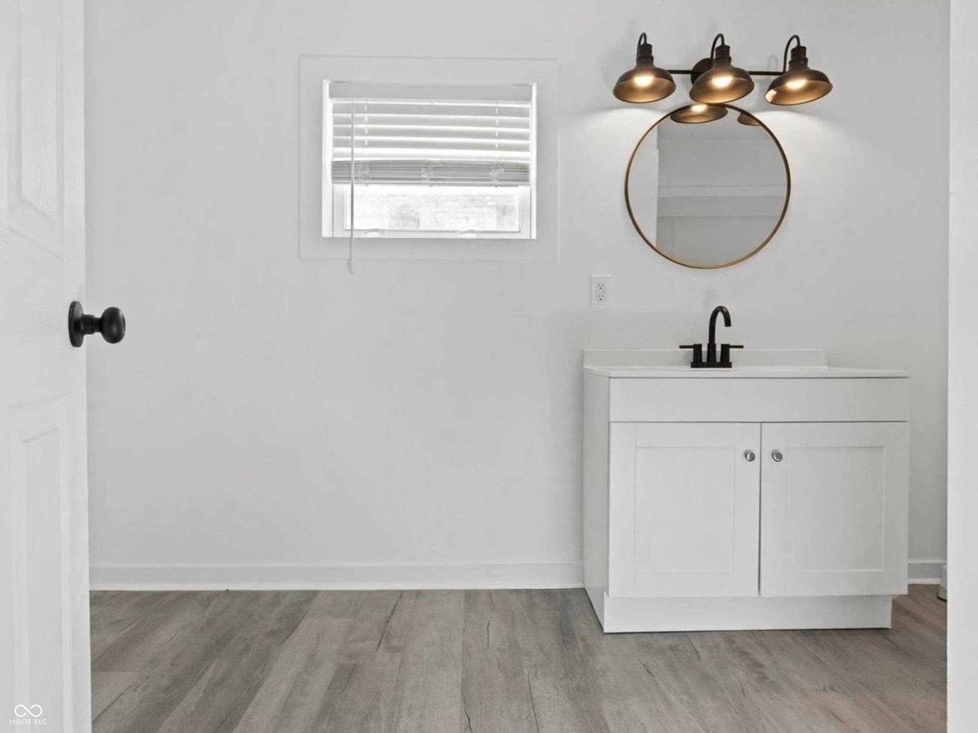 White vanity with integrated sink, matte black faucet, and circular mirror