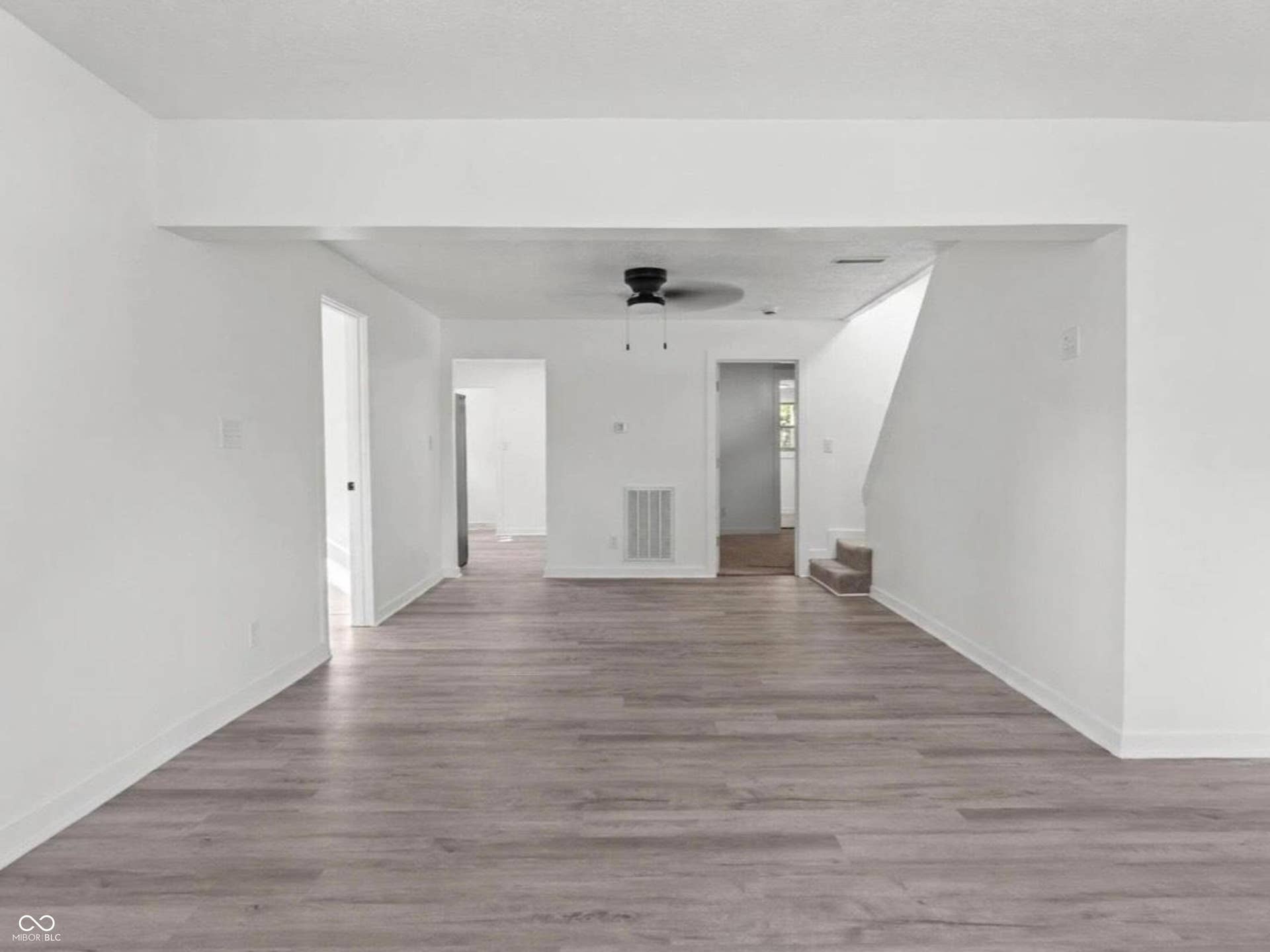 Spacious interior with neutral white walls, wood-finish flooring, and a ceiling fan