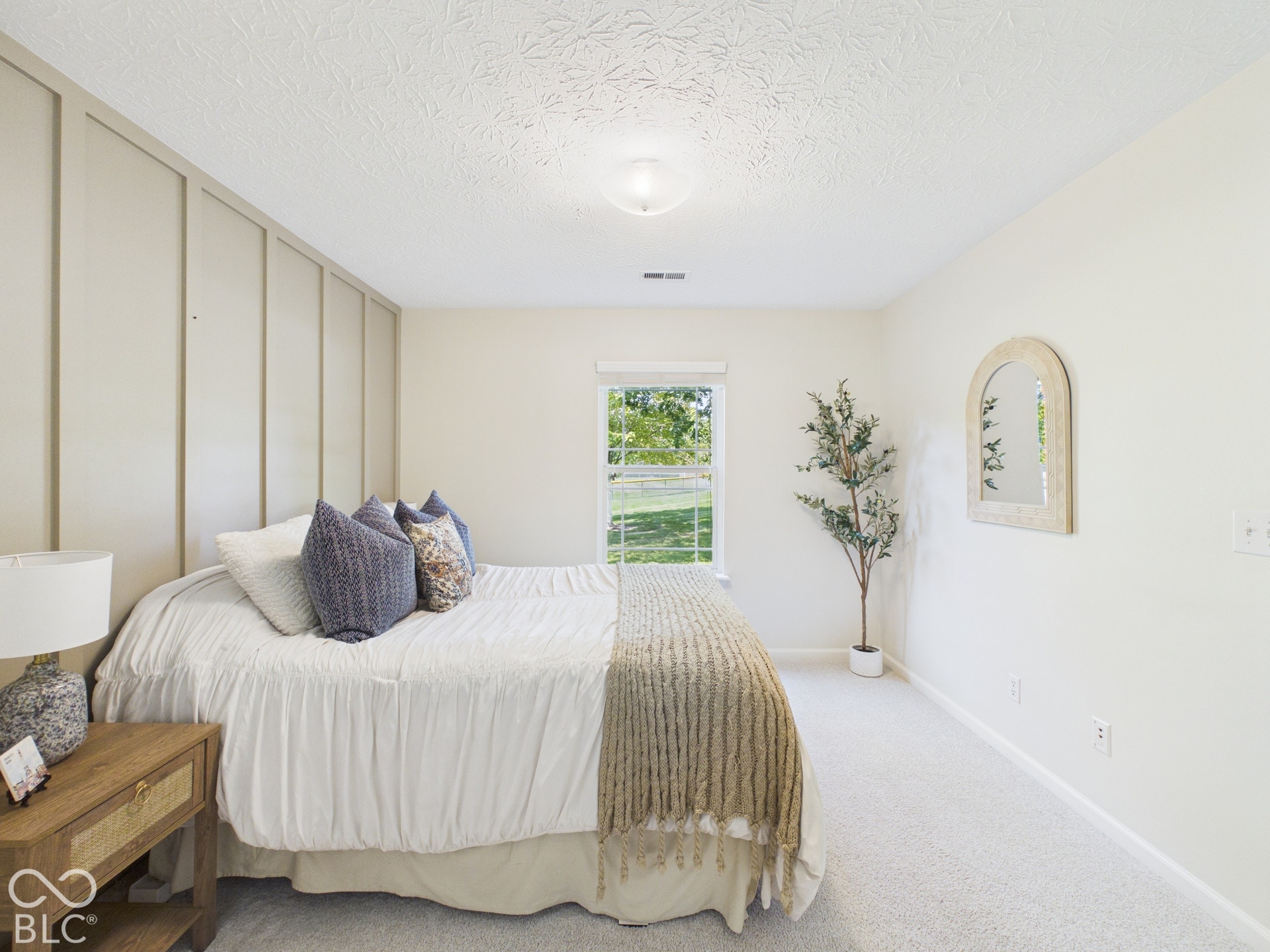 Textured ceiling, wall paneling, window with outdoor scenery, wall-to-wall carpeting, and a built-in light fixture