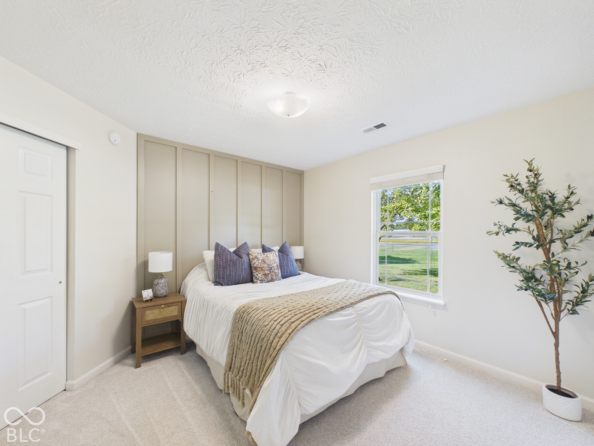 Carpeted flooring, window with roller shade, recessed lighting, and wall paneling