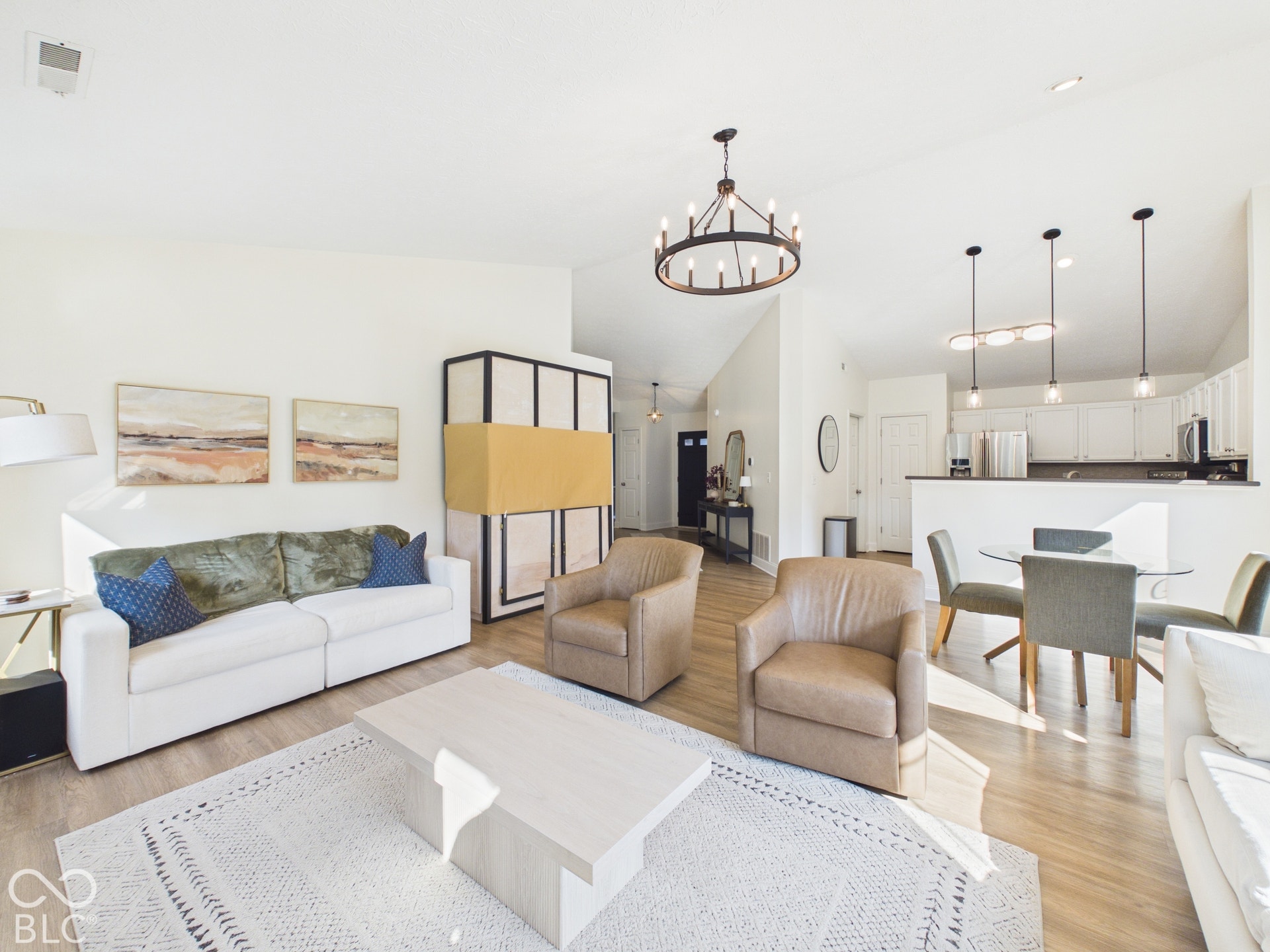 Vaulted ceilings with a circular chandelier, wood-finish flooring, and white cabinetry with stainless steel appliances