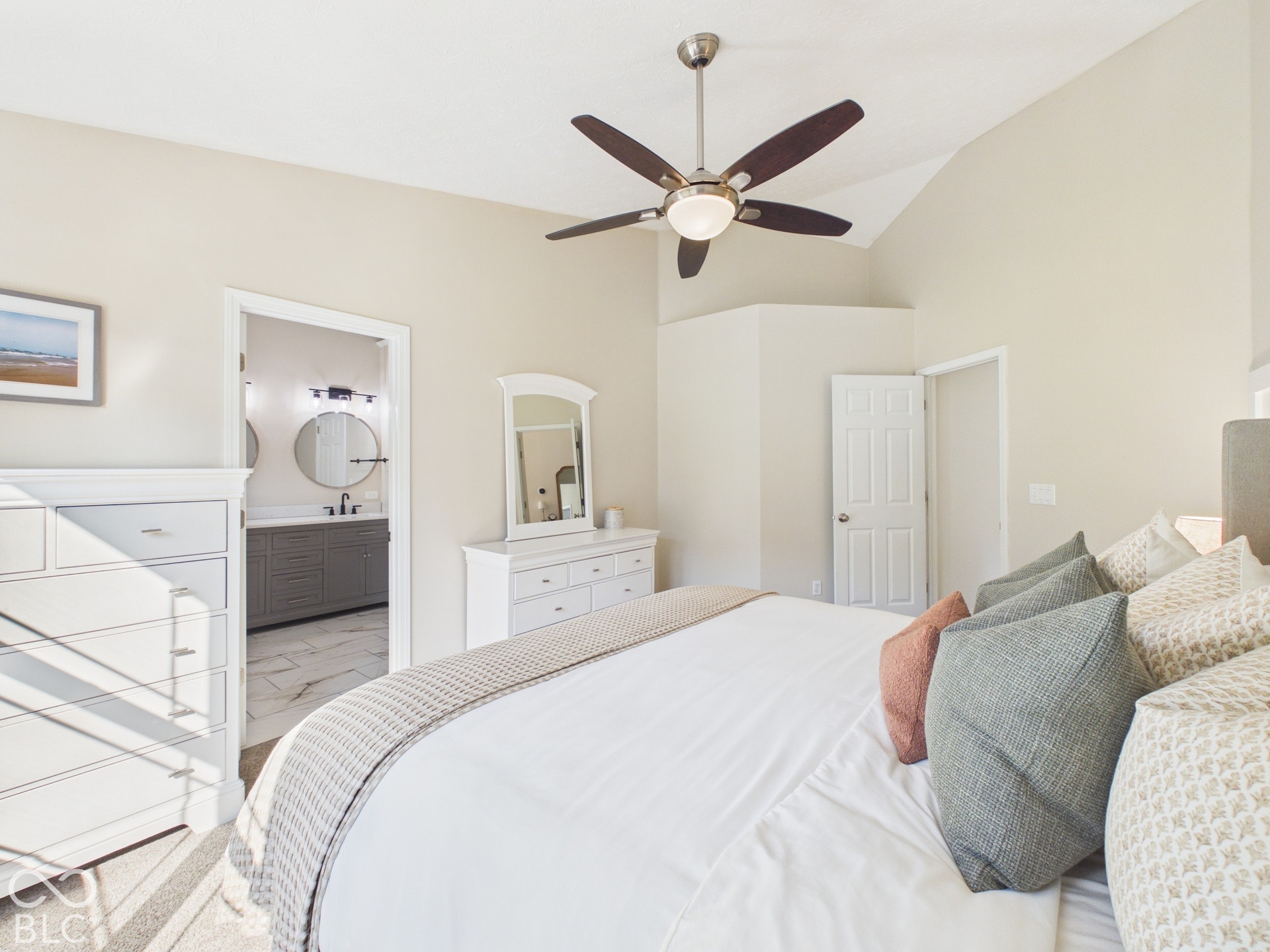 Vaulted ceiling, ceiling fan with integrated lighting, and an open doorway to a bathroom with a dual vanity