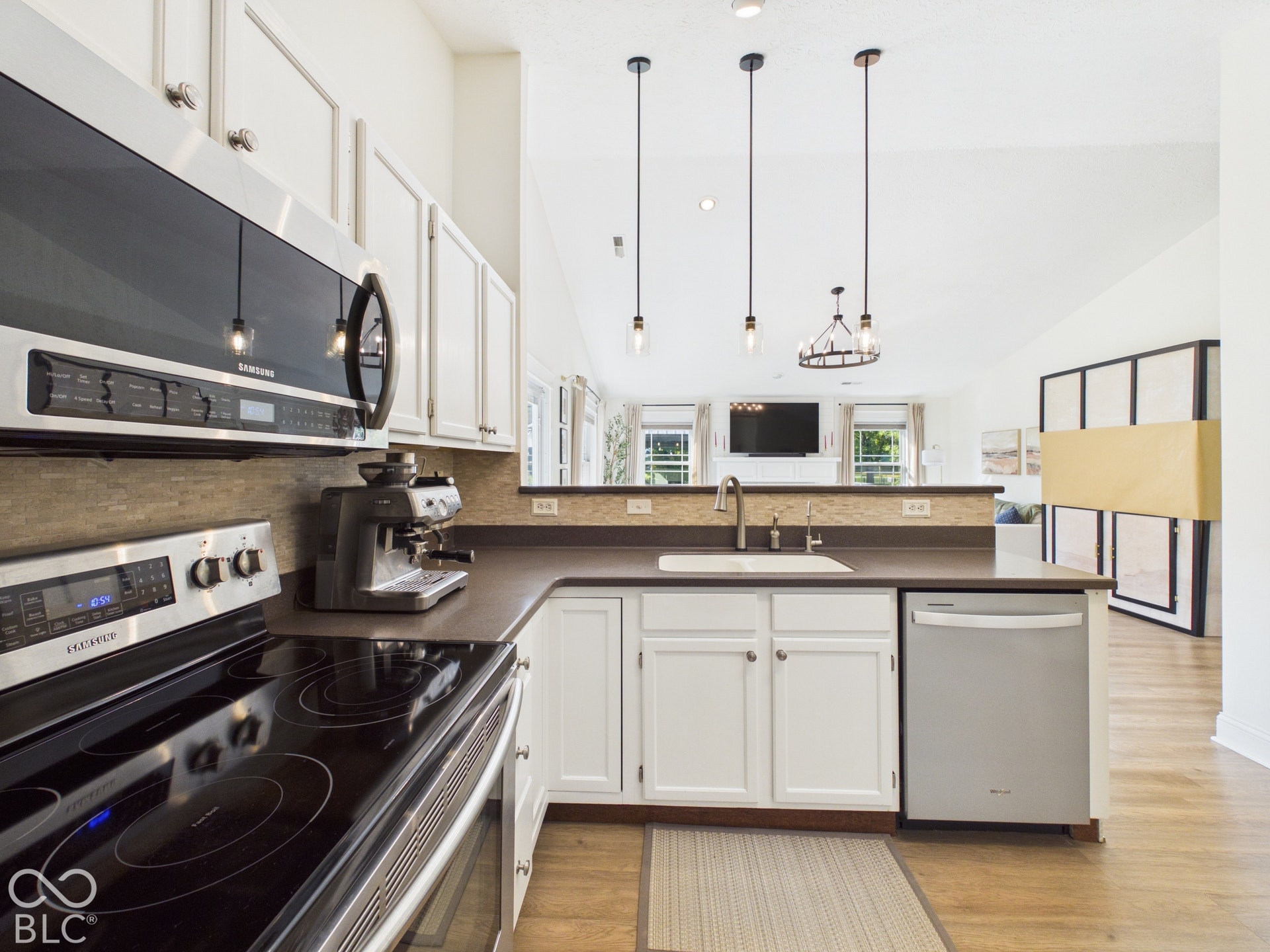 White cabinetry with brushed nickel hardware, stainless steel appliances, dark countertops, and a tile backsplash