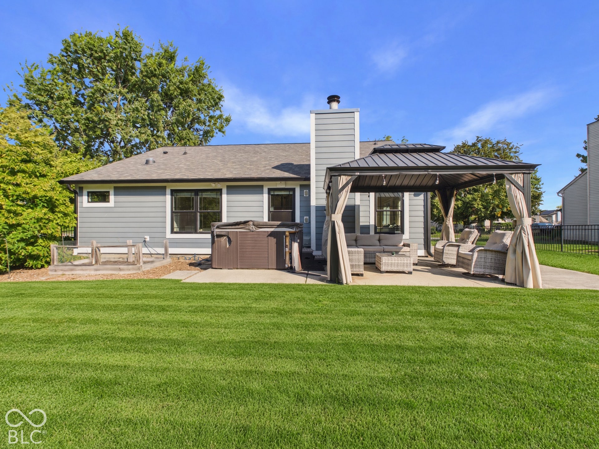Expansive backyard featuring a concrete patio, a permanent gazebo structure, and a built-in spa