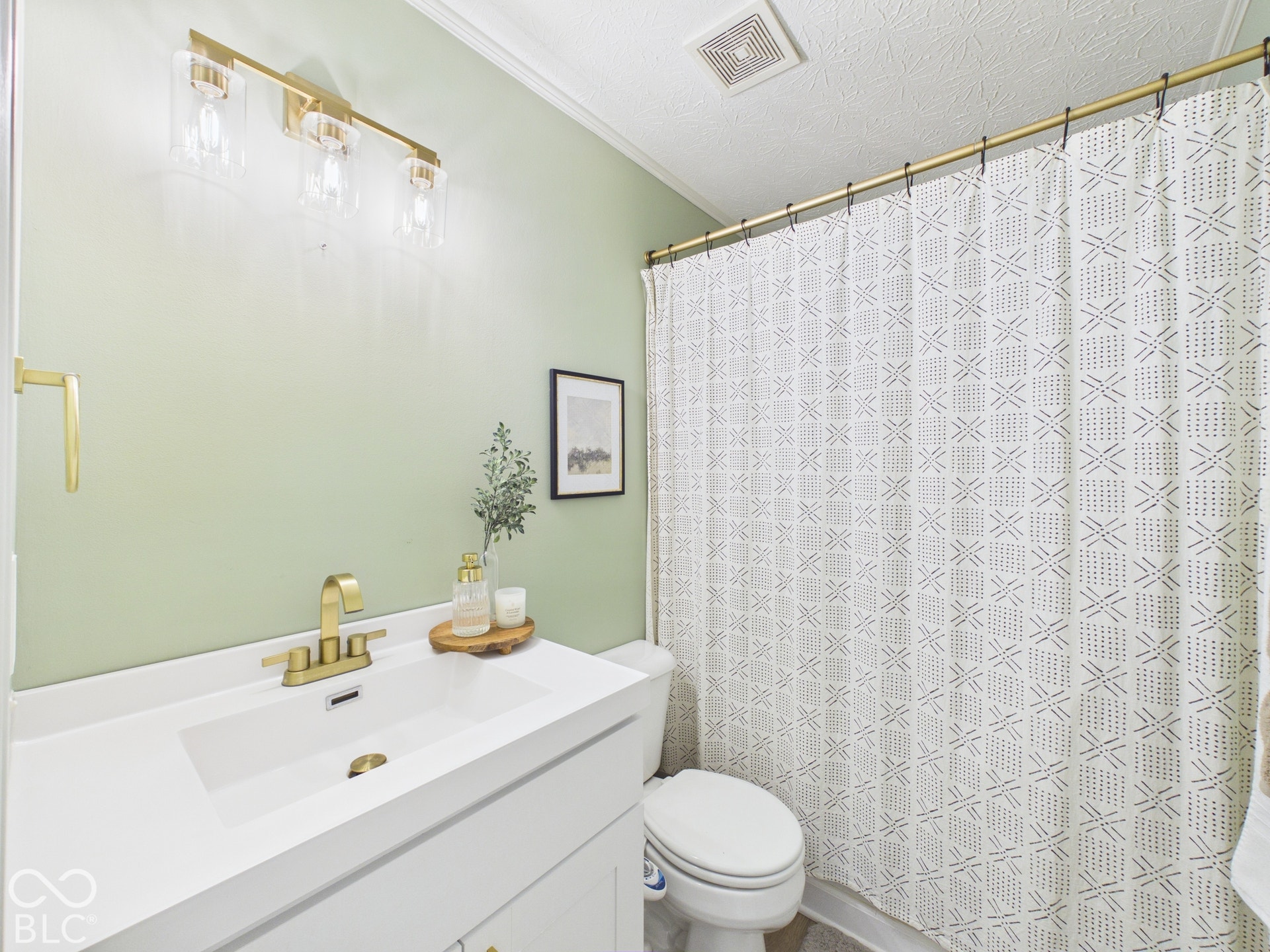 White vanity with integrated sink, brass-finish faucet, and coordinating vanity lighting