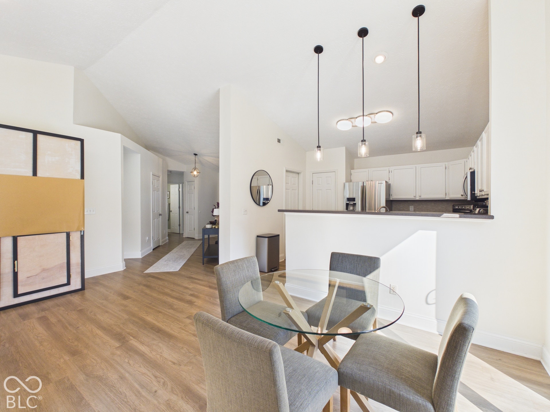 Open-concept living area with vaulted ceilings, wood-finish flooring, recessed lighting, and a breakfast bar