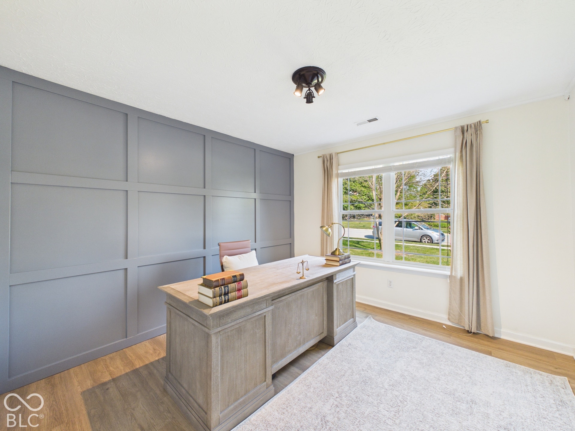 Wall paneling accent, wood-finish flooring, natural light through a large window, recessed lighting, and a flush-mount ceiling fixture