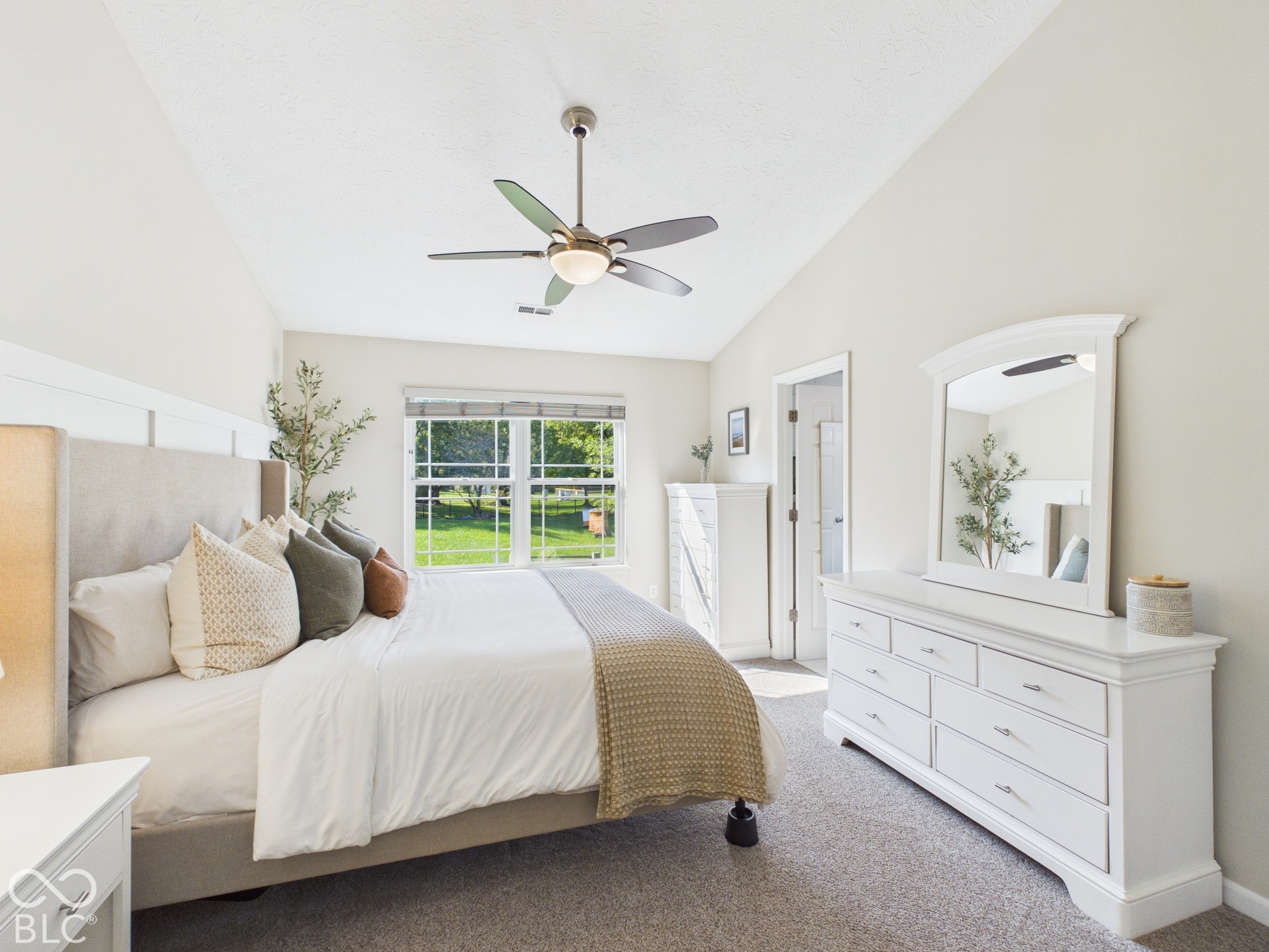 Vaulted ceiling with a ceiling fan, carpet flooring, and a large window