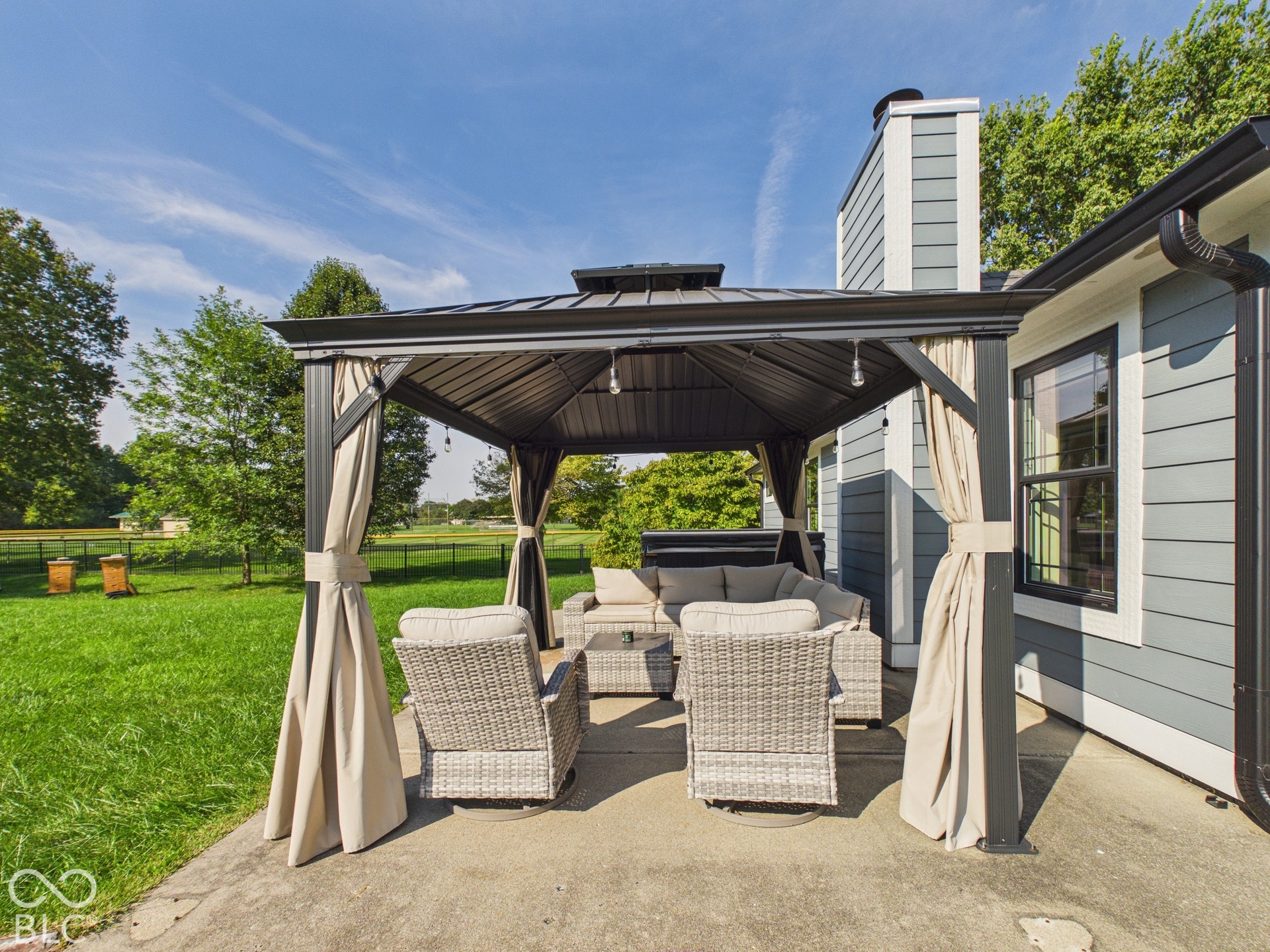 Patio with a metal-framed gazebo, privacy curtains, and string lighting