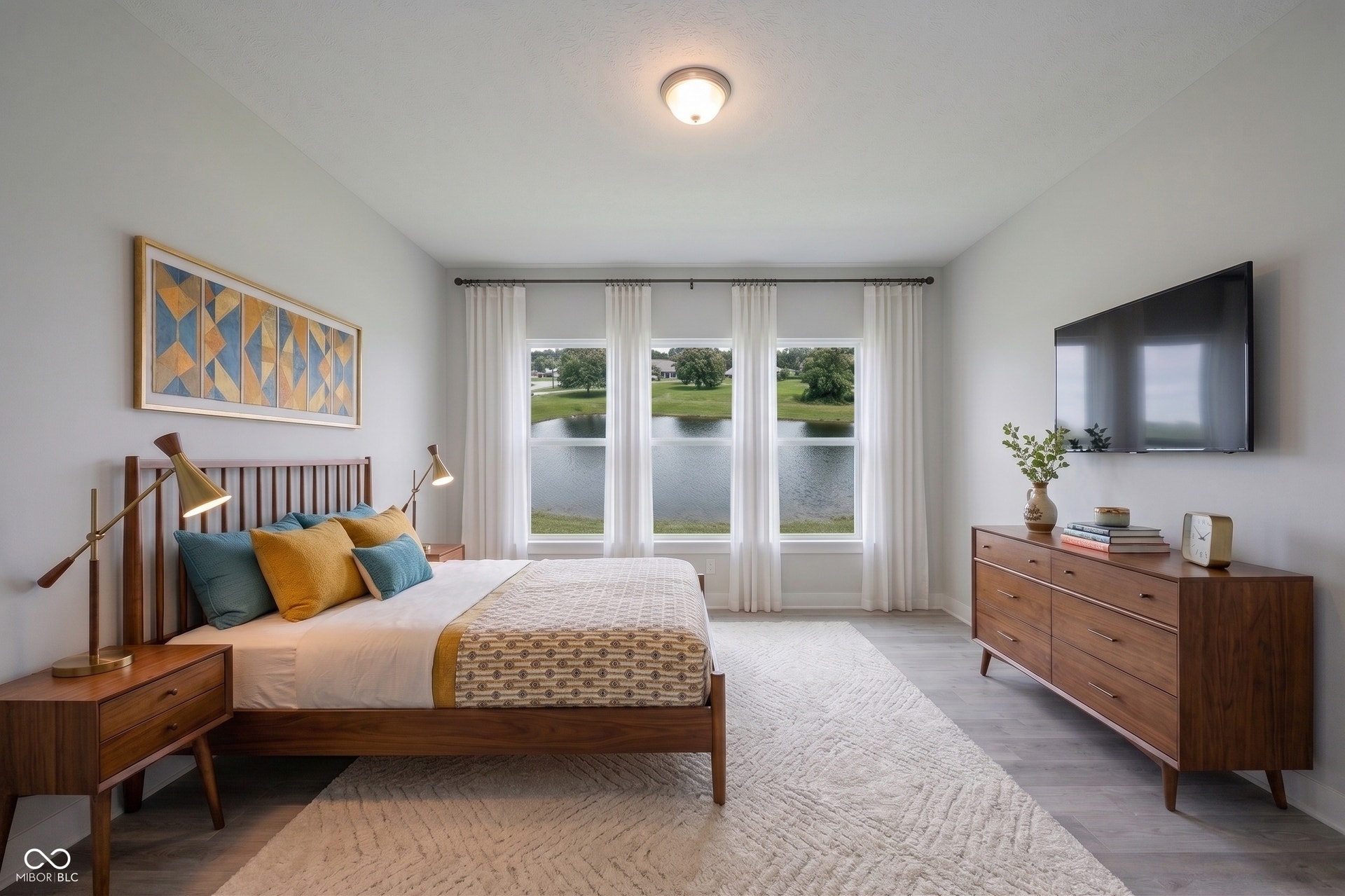 Primary Bedroom is on the main floor.  It's spacious has luxury laminated hardwood flooring and the pond view.  This photo has been virtually staged.