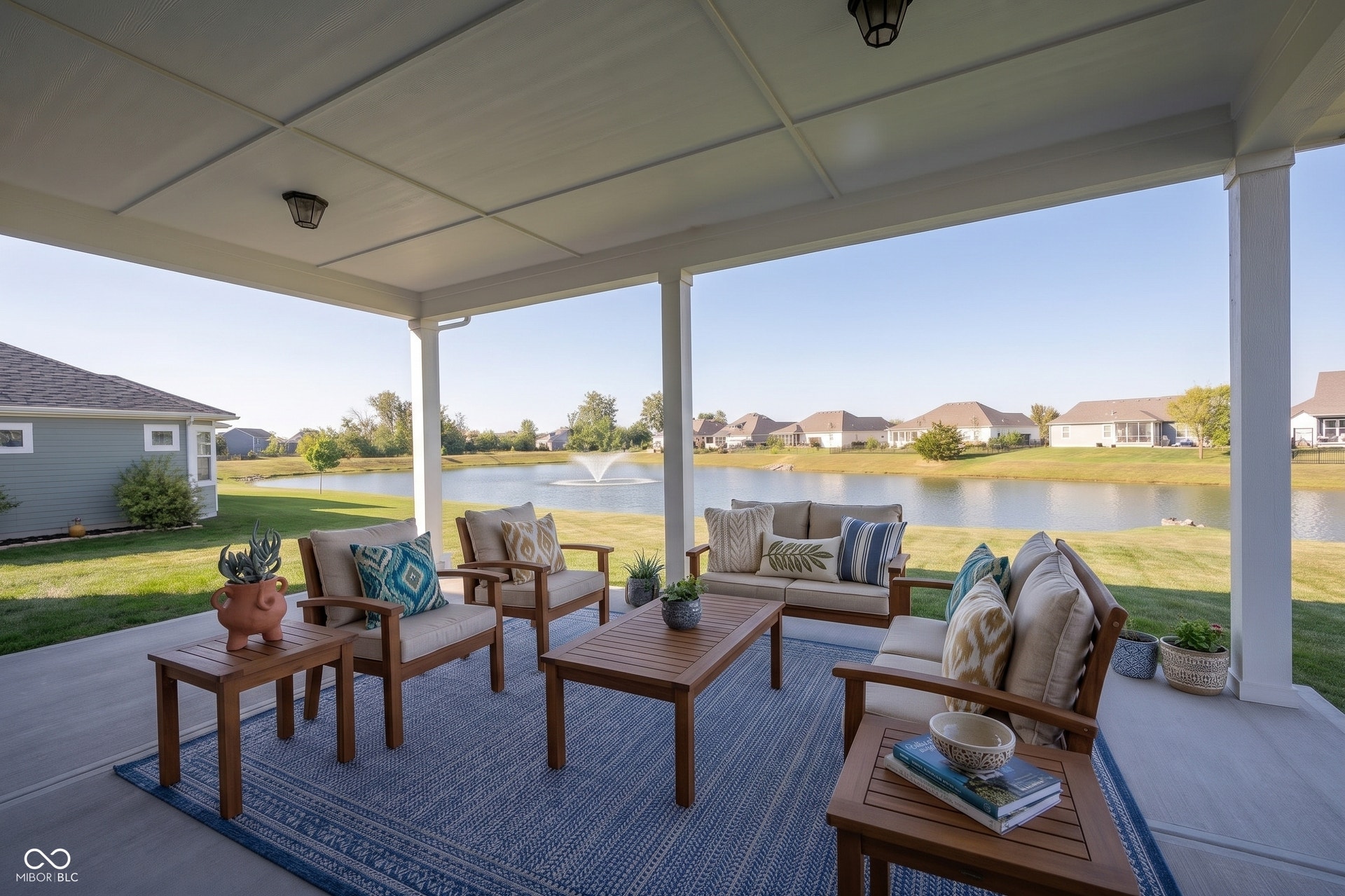 Covered lanai in the backyard overlooking the expansive backyard space and pond with a fountain.  This photo has been virtually staged.