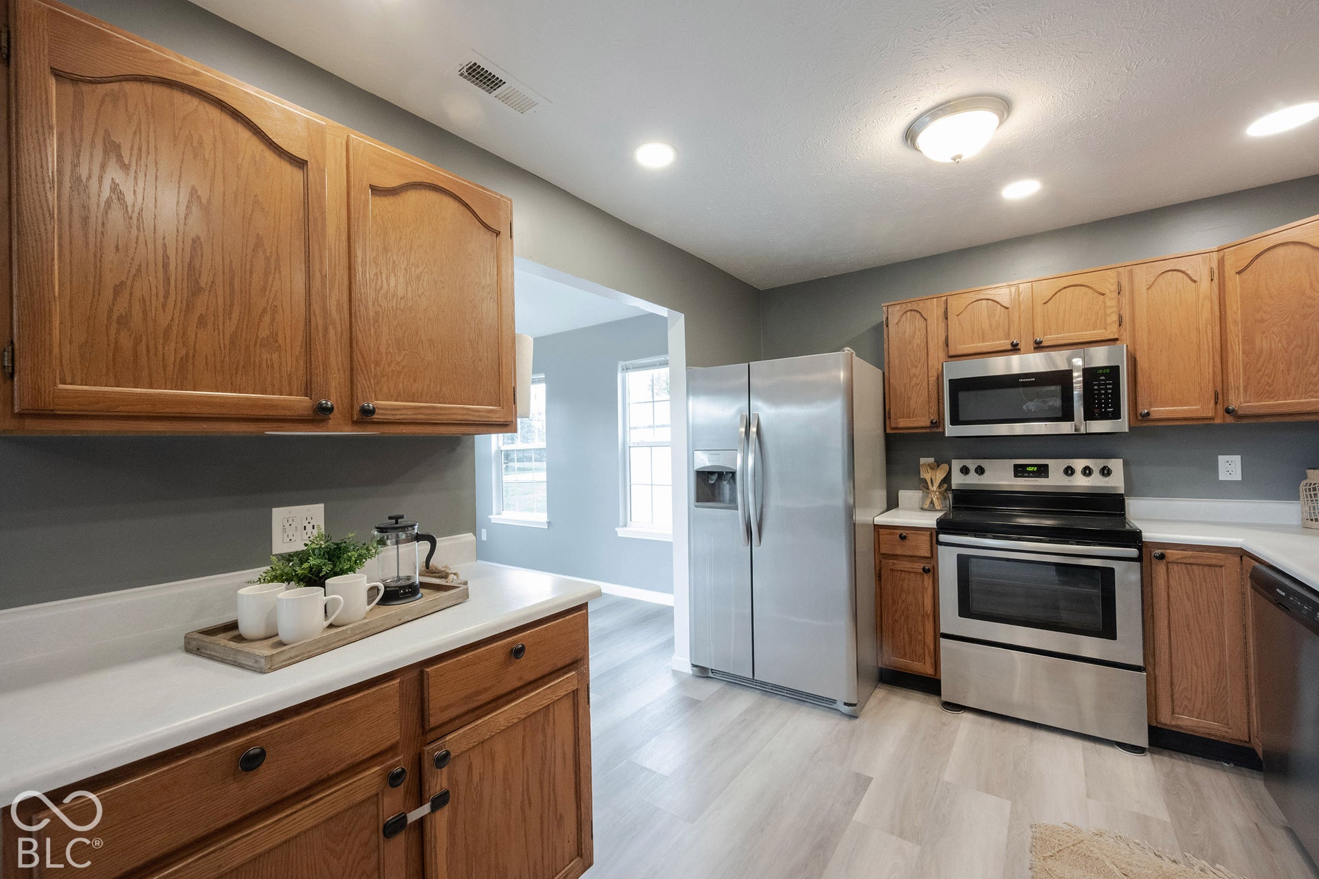 The kitchen features wood cabinetry, white countertops, and more wood-finish floors!