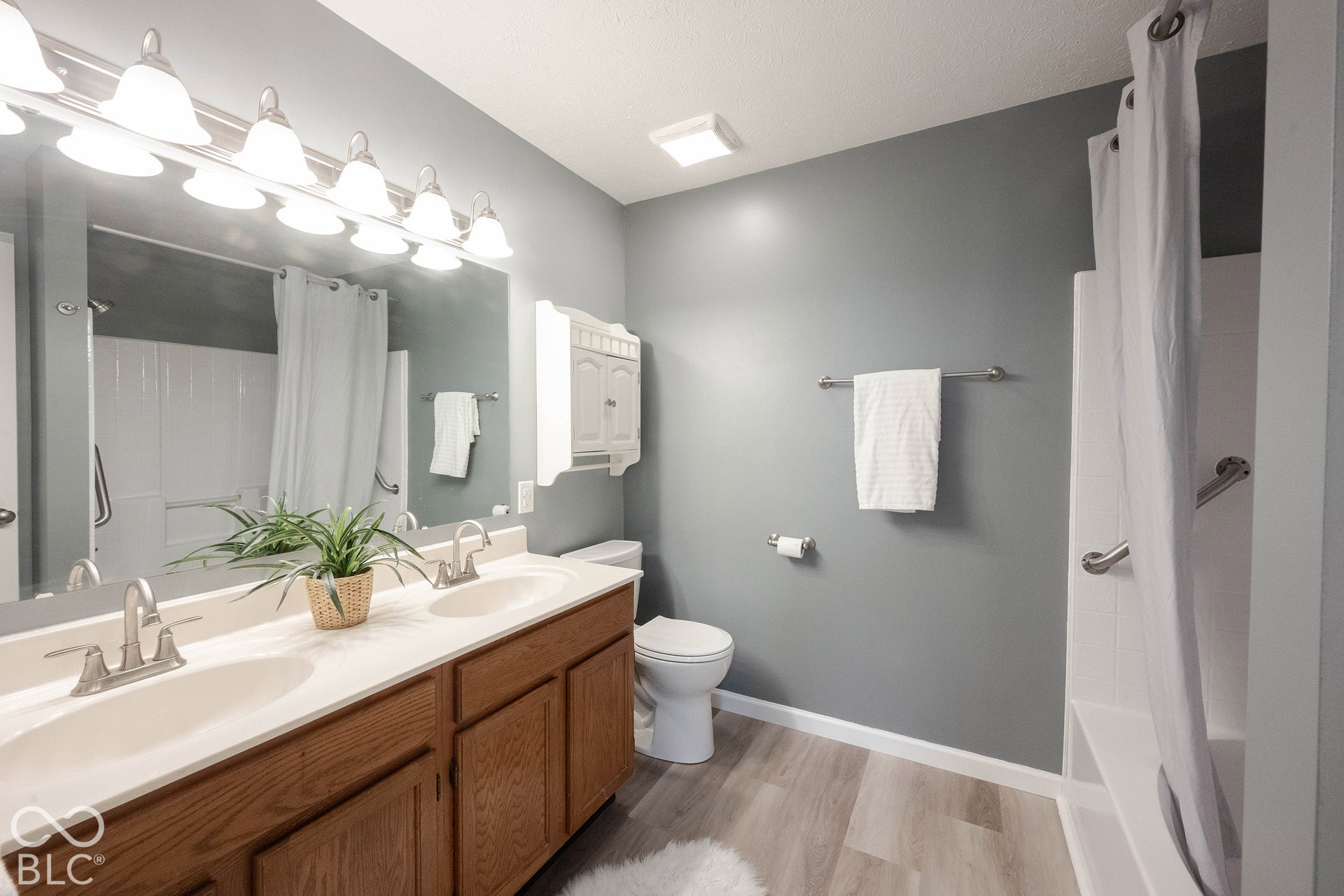 The primary bathroom features a double vanity, wood-finish cabinetry, and more wood-finish flooring.