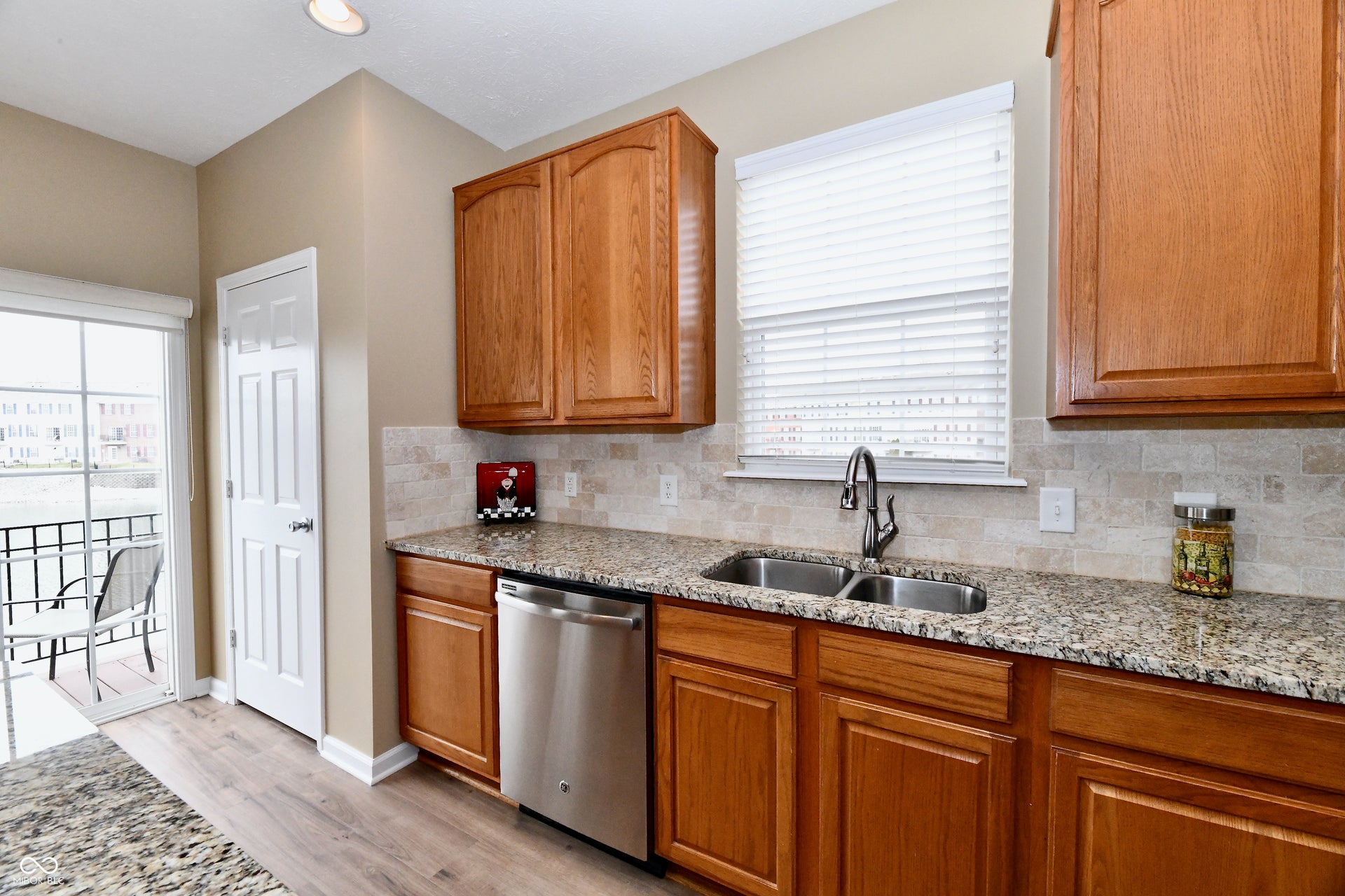 Hardwood-finish flooring, stainless steel dishwasher, double basin sink, granite countertops, and wood cabinetry