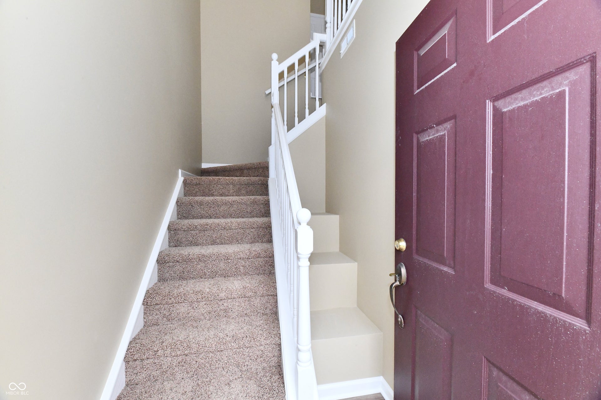 Entryway featuring an interior door with paneling, carpeted staircase, and white painted balusters