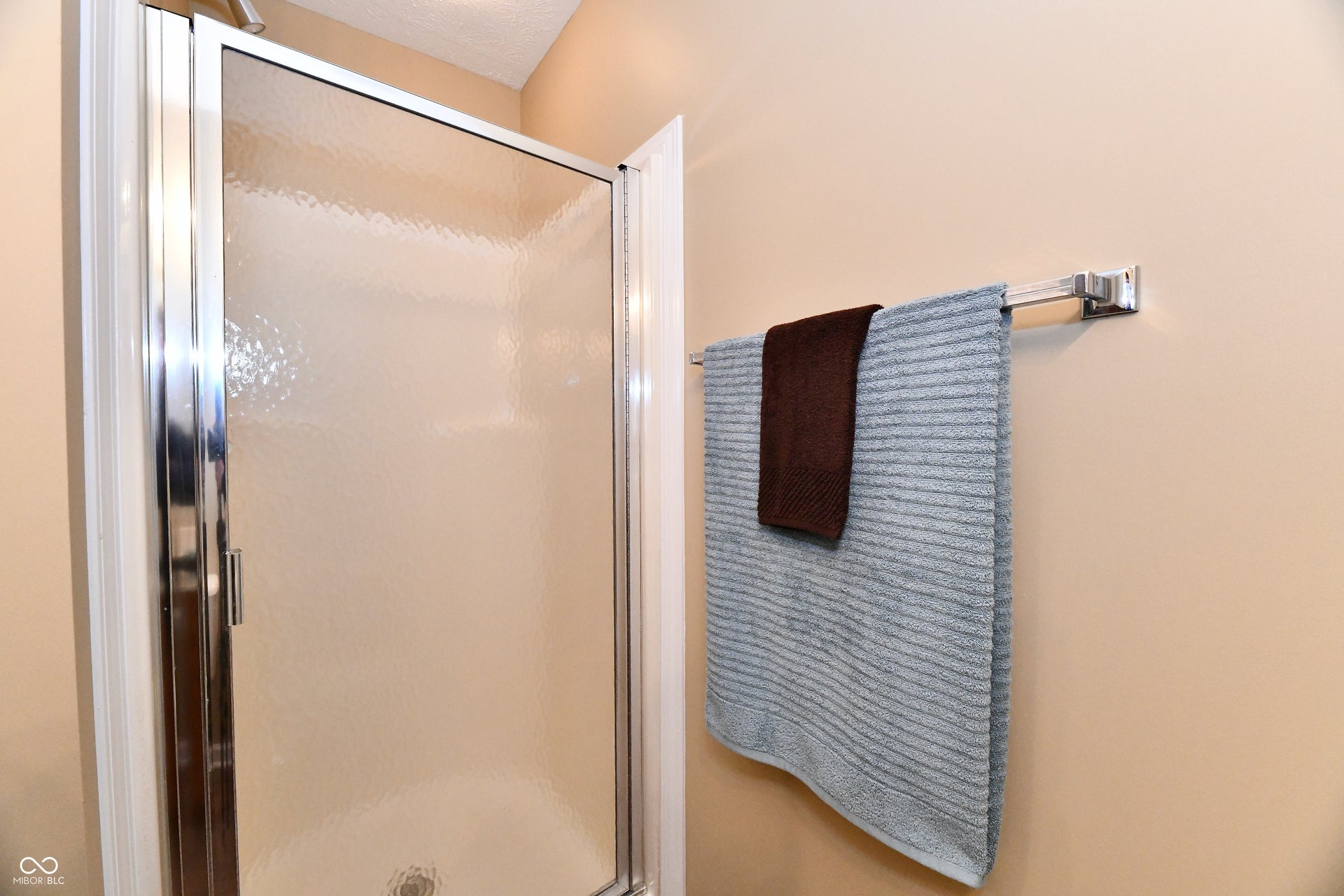 Shower enclosure with textured glass panel and polished chrome frame