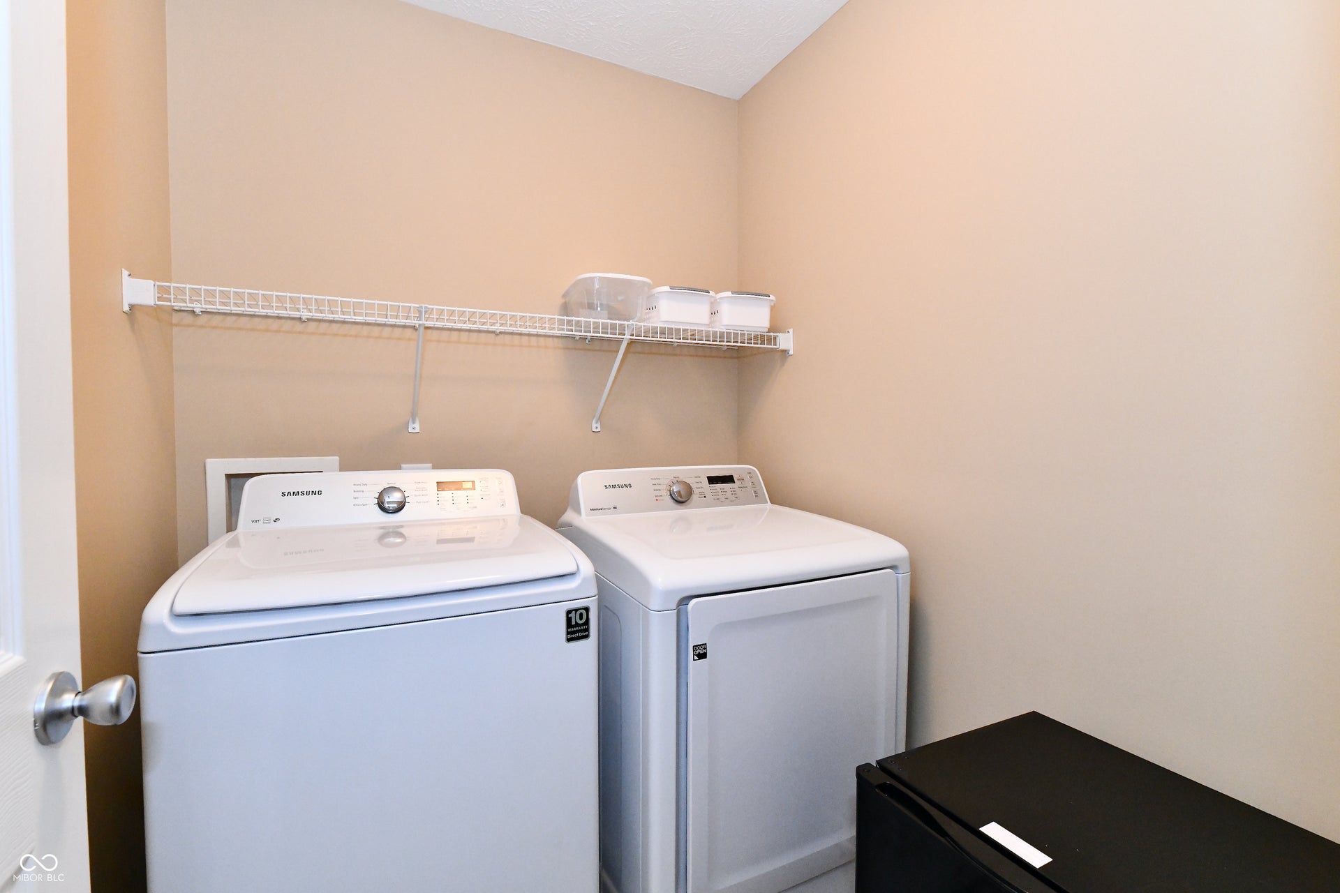 Laundry area with light-toned walls and a white wire shelving unit