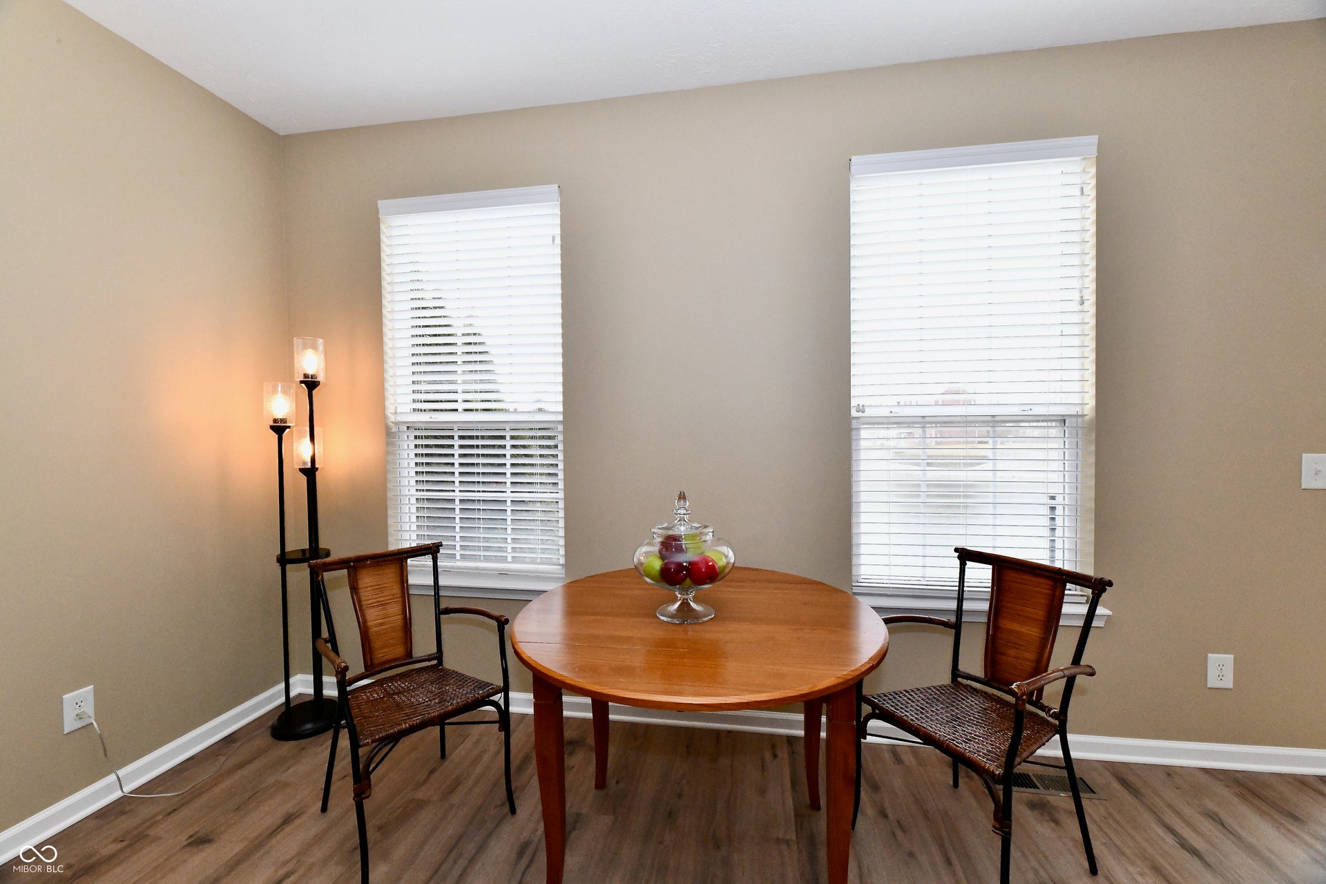 Warm wall color with two windows, featuring wood-finish flooring