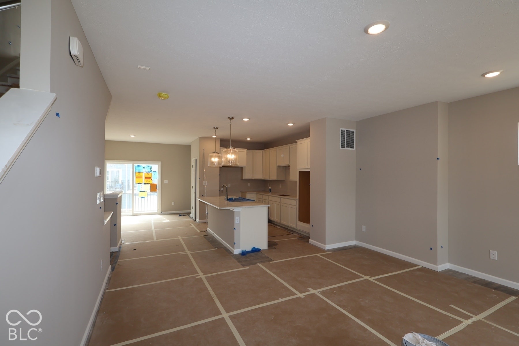 Open-concept living area with recessed lighting, light-toned walls, and a kitchen featuring white cabinetry, a central island, and pendant lighting