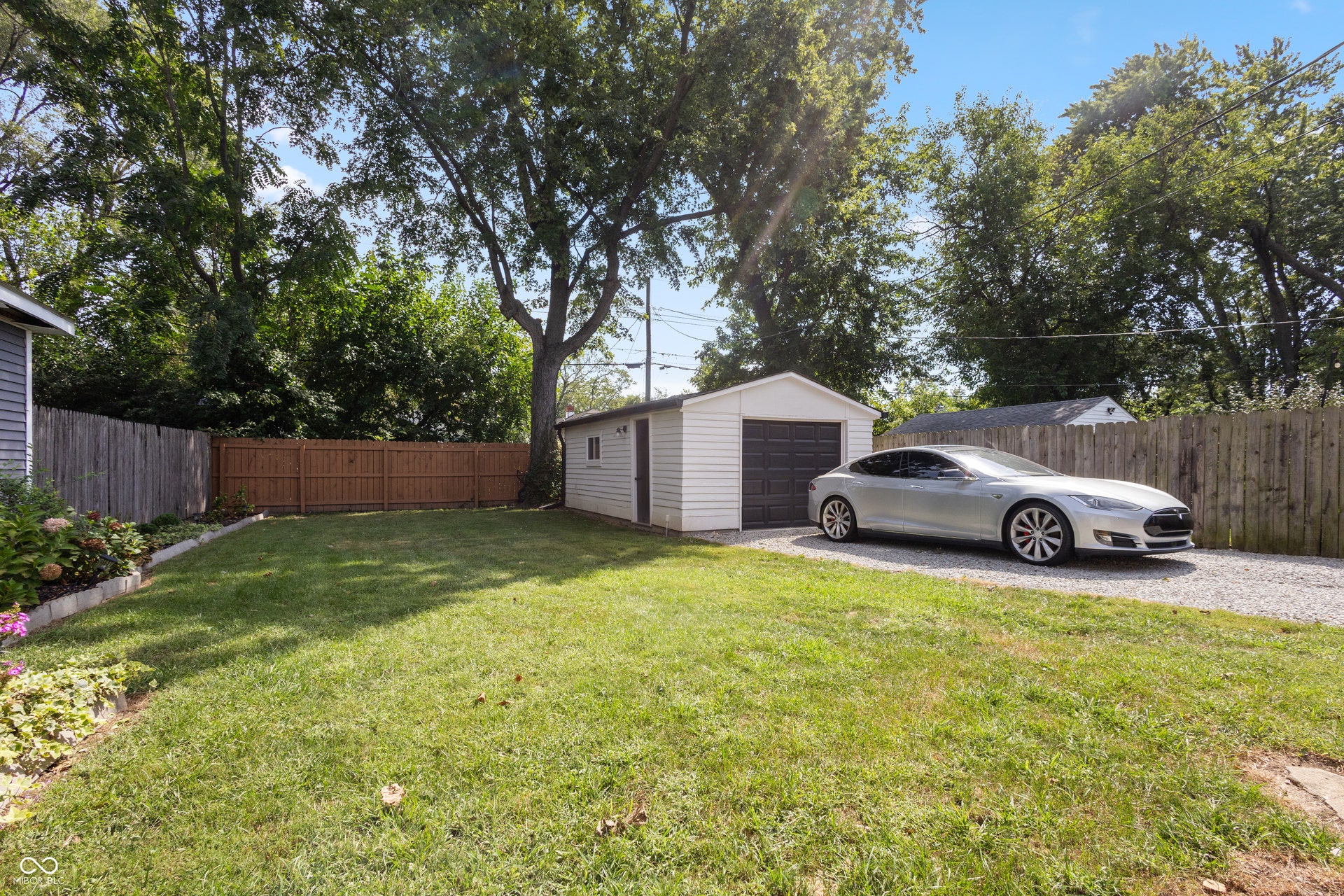 4927 Caroline Avenue, Indianapolis, IN 46205 Fenced backyard with a gravel driveway, detached garage, and mature trees