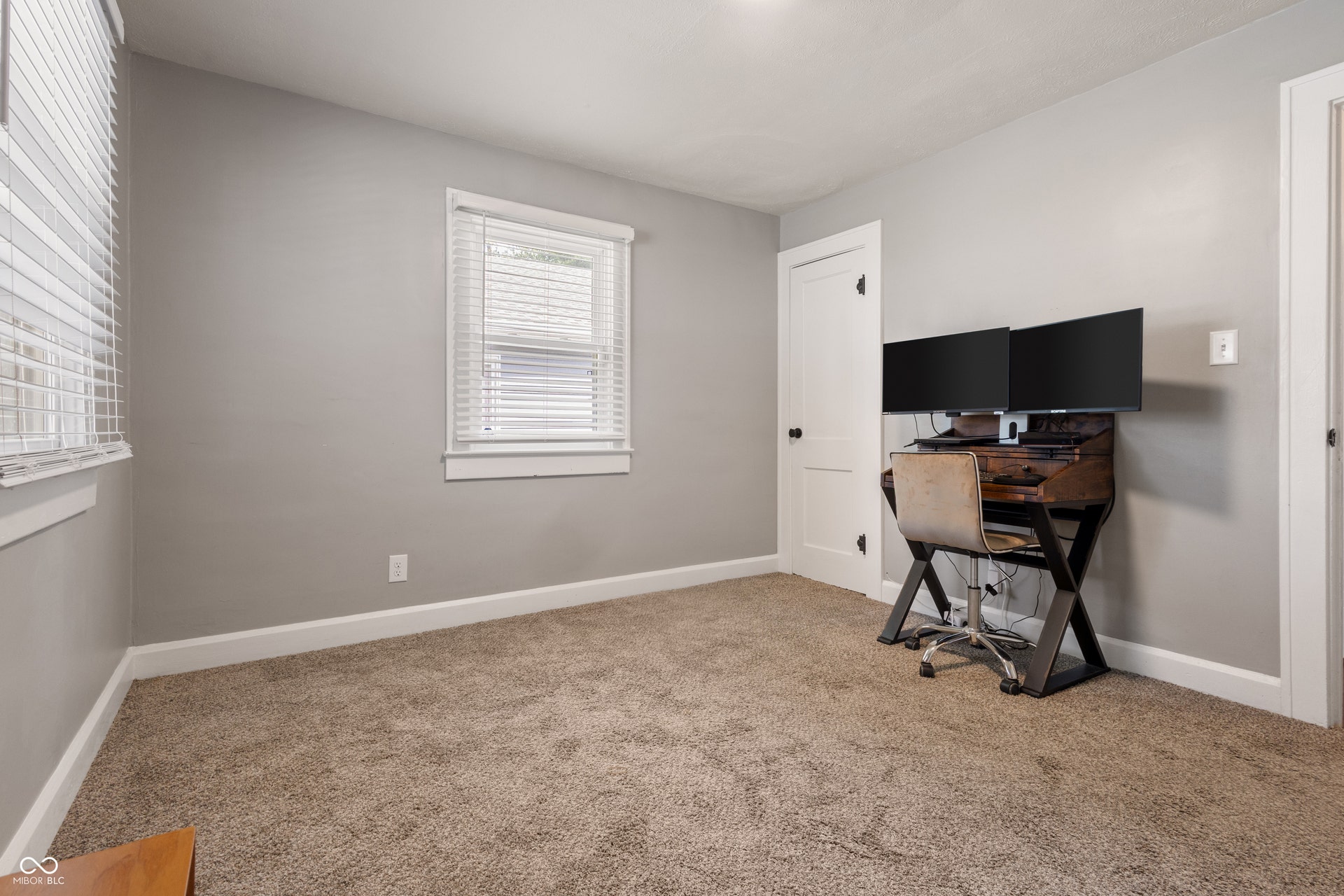 4927 Caroline Avenue, Indianapolis, IN 46205 Neutral wall color, carpet flooring, multiple windows with blinds, white trim, and a white door with dark hardware
