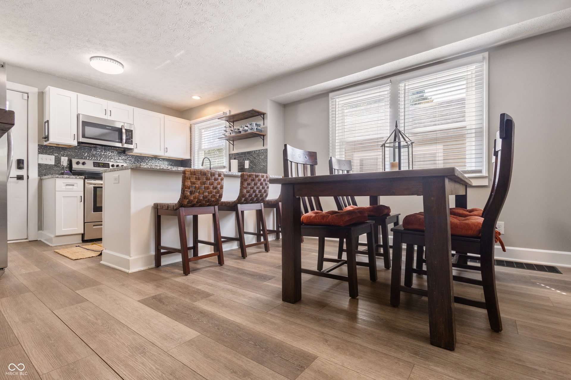 4927 Caroline Avenue, Indianapolis, IN 46205 Kitchen with wood-finish flooring, white cabinetry, stainless steel appliances, and a tiled backsplash