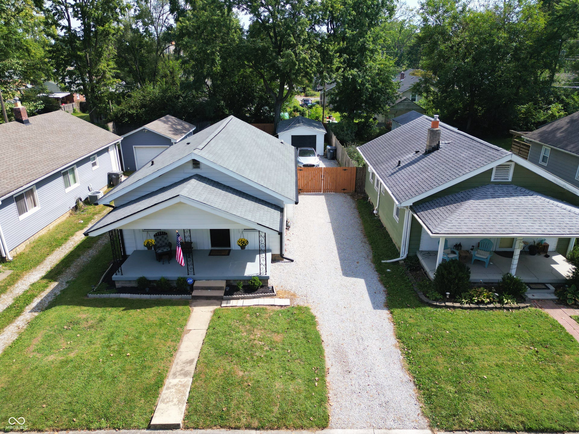 4927 Caroline Avenue, Indianapolis, IN 46205 Gable roofline, covered front porch, gravel driveway, detached garage structure, wood privacy fence