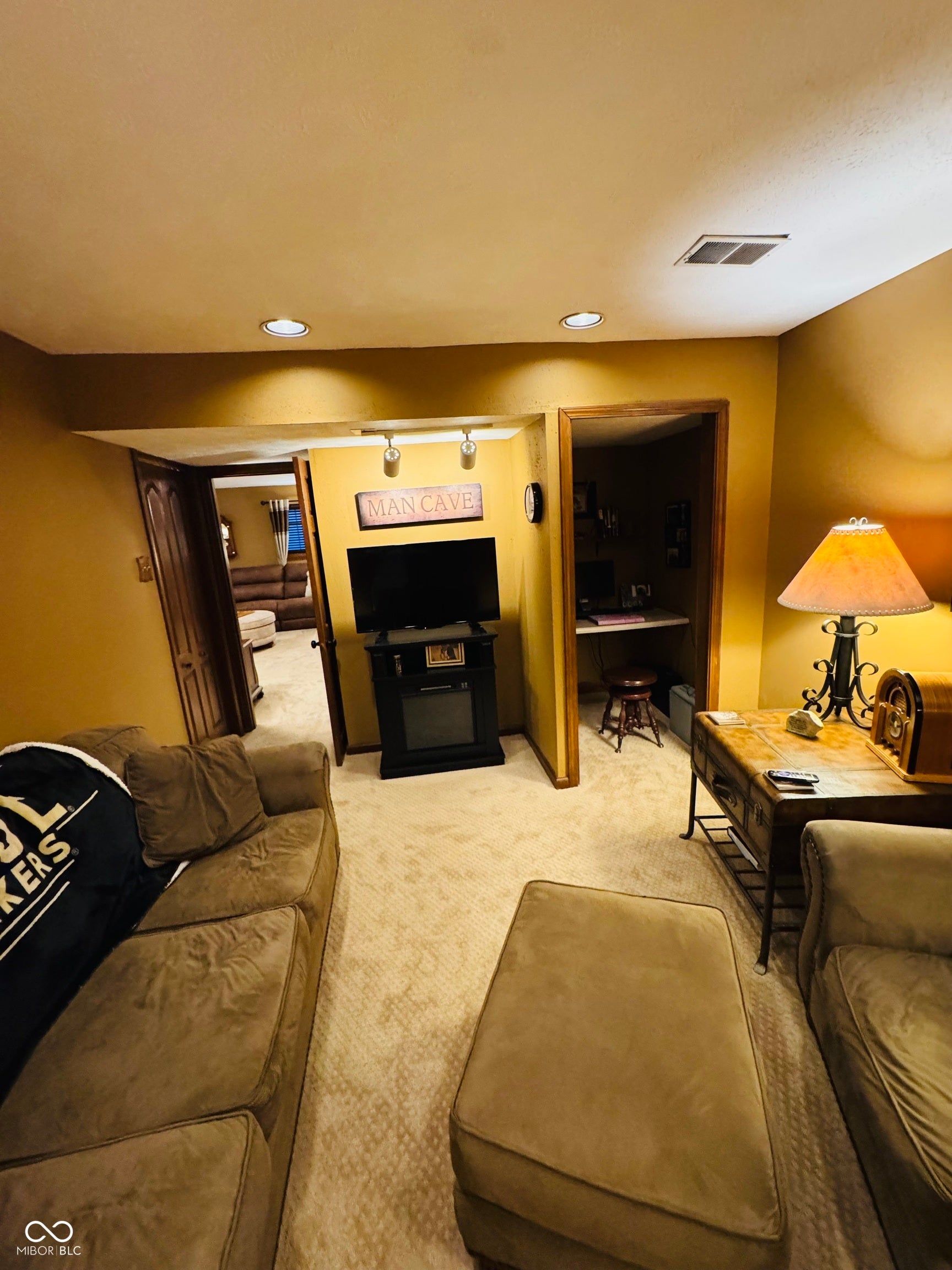 Recessed ceiling lighting, patterned carpet flooring, and a built-in media console
