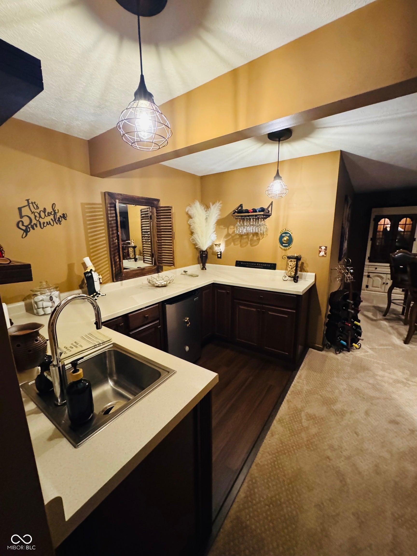 L-shaped counter with undermount sink, dark wood-finish cabinetry, and pendant lighting