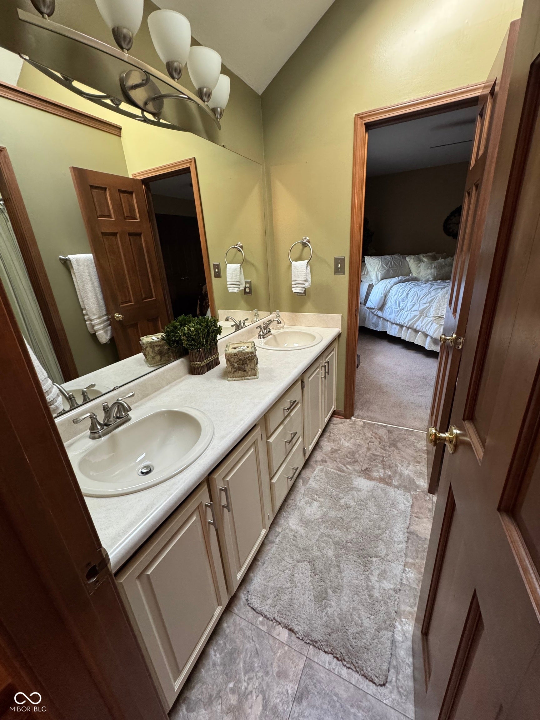 Dual vanity with integrated sinks, wood-finish cabinetry, and overhead bar lighting
