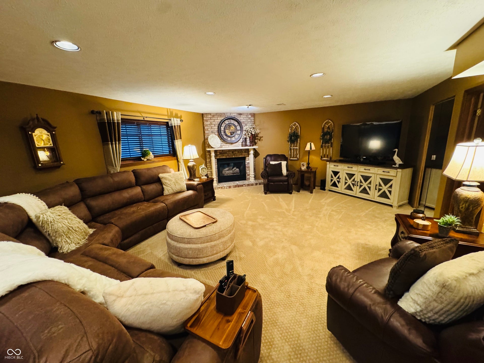 Spacious room featuring recessed lighting, carpeted flooring, and a stone-clad fireplace with a mantel