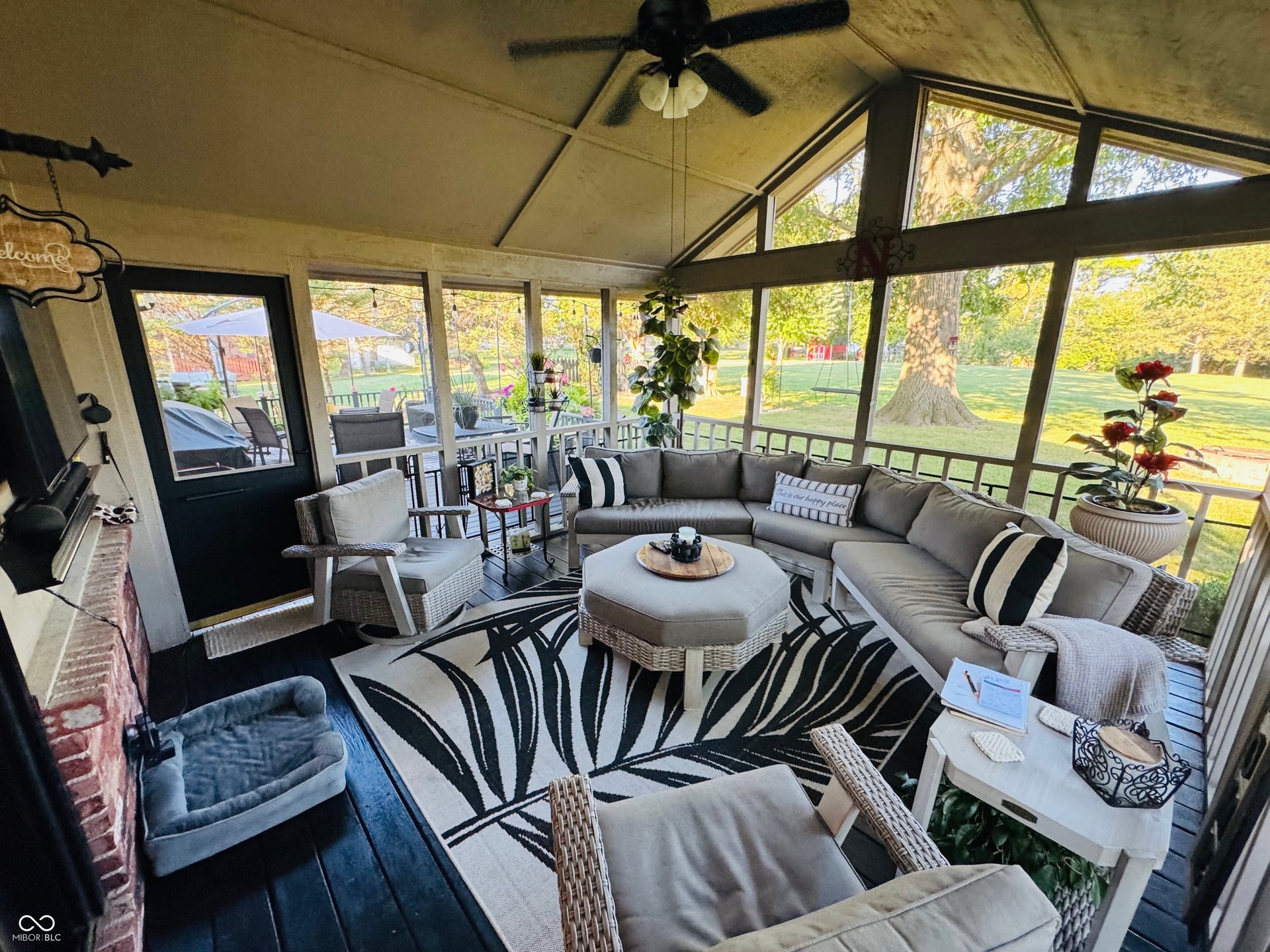 Screened porch with vaulted ceiling, exposed rafters, and dark wood-finish flooring