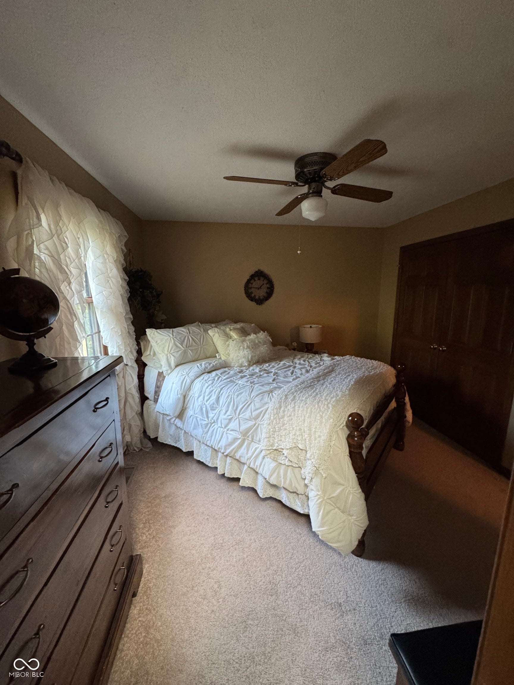 Carpeted flooring, ceiling fan with light fixture, and wood-finish double closet doors