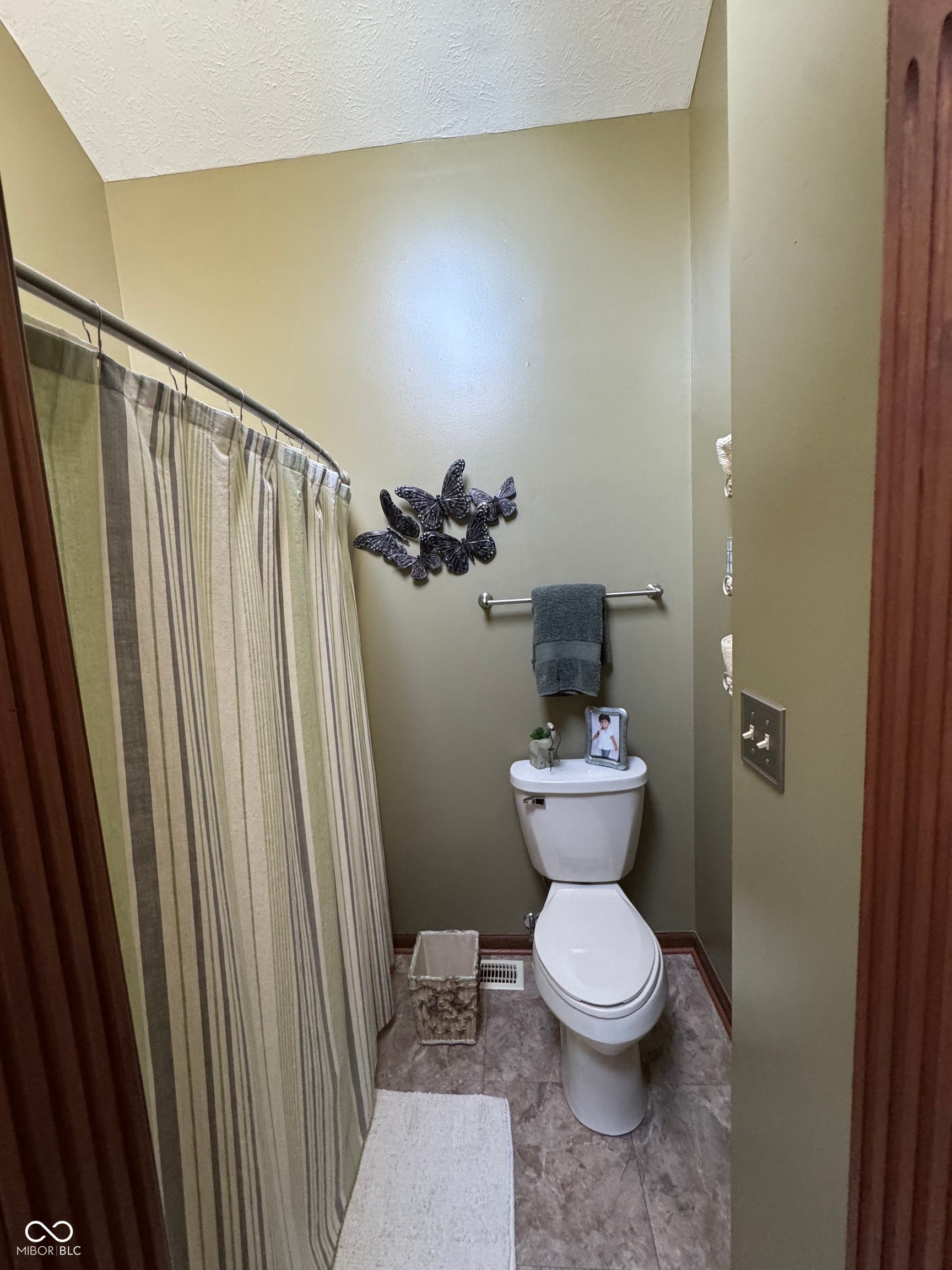 Full bathroom featuring a white toilet, chrome towel bar, and gray tone flooring