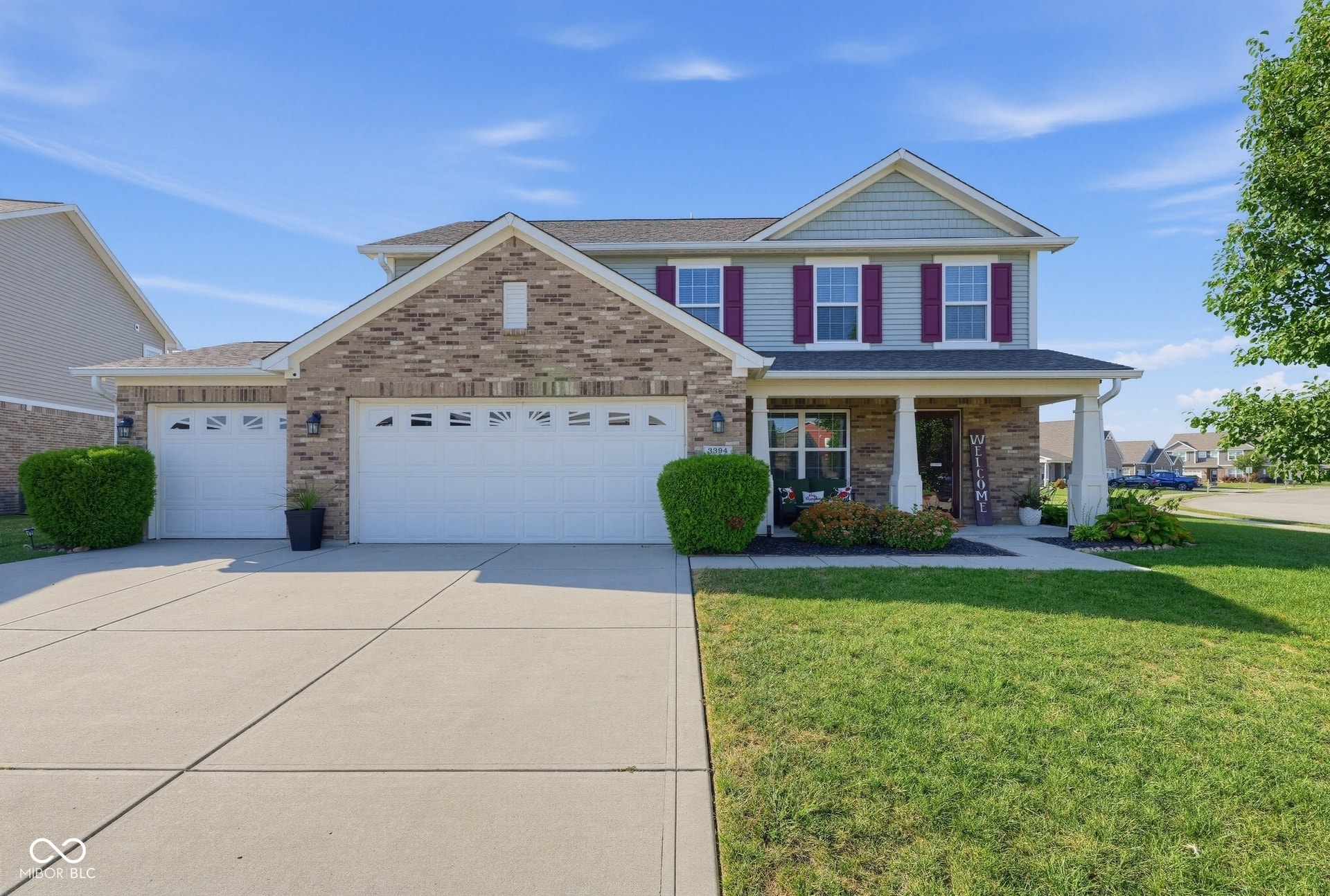 3394 S Bennett Drive, New Palestine, IN 46163 Two-story residence featuring brick and siding exterior, an attached two-car garage, a covered front porch, and a concrete driveway
