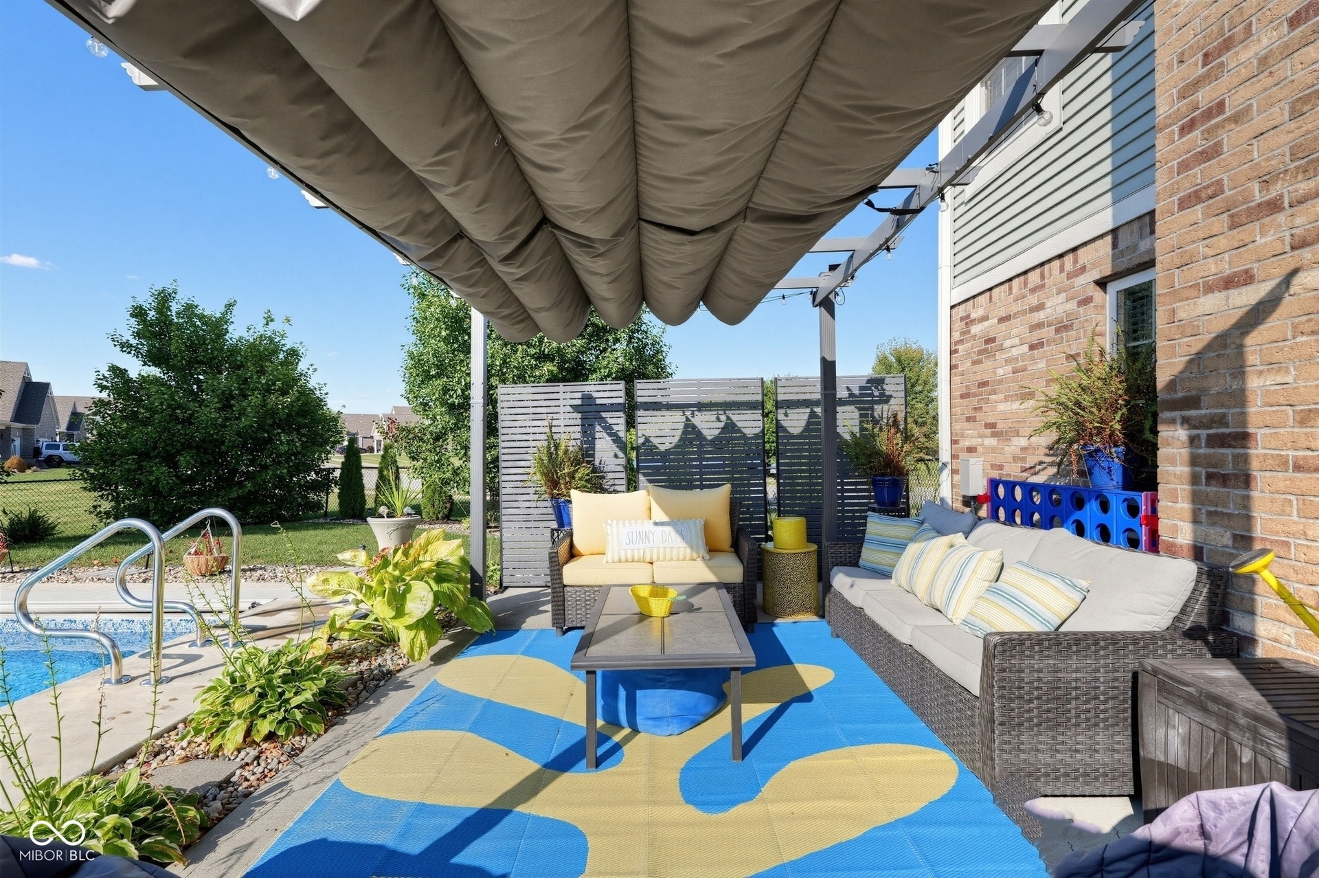 3394 S Bennett Drive, New Palestine, IN 46163 Outdoor patio with retractable pergola, brick and siding exterior, privacy screen, and an in-ground pool