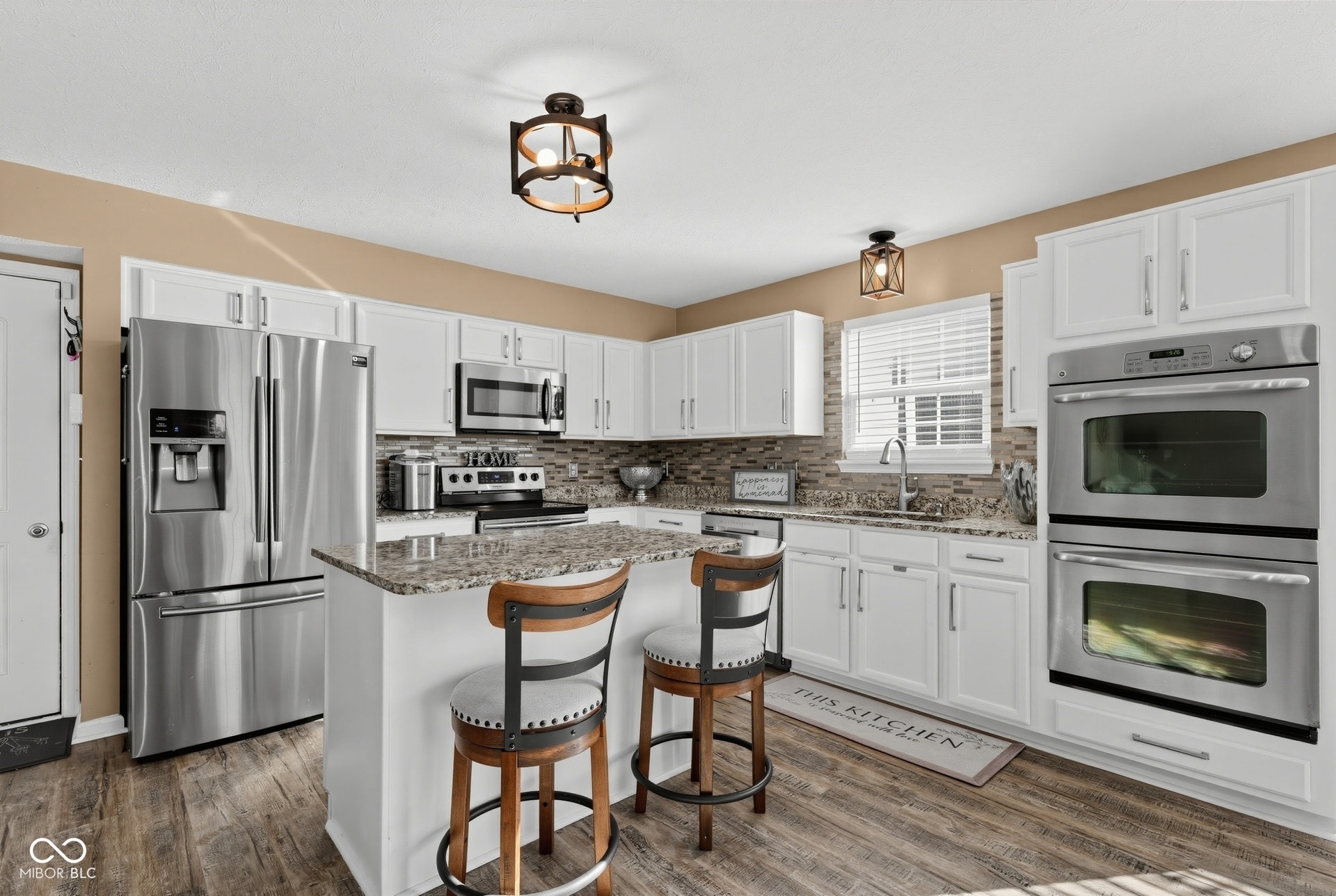3394 S Bennett Drive, New Palestine, IN 46163 White cabinetry with stainless steel appliances with a nice double oven, granite countertops, and a tile backsplash