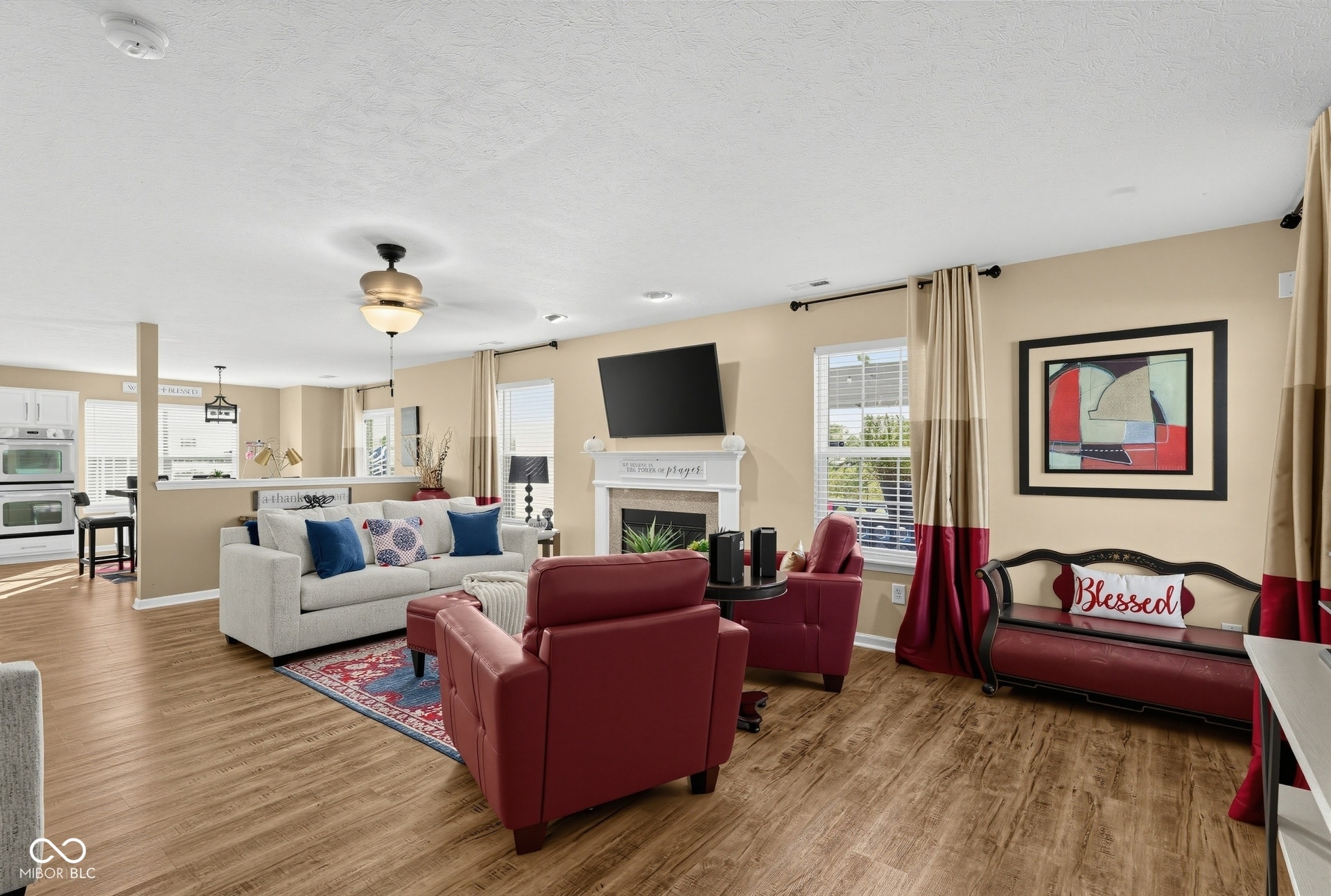 3394 S Bennett Drive, New Palestine, IN 46163 Open-concept living space featuring laminate-finish flooring, a ceiling fan with integrated lighting, and a fireplace with a white mantel
