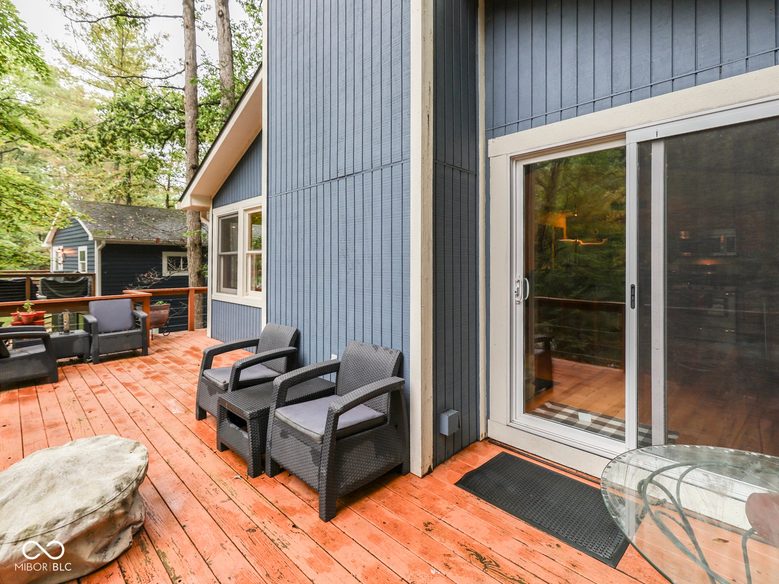 Wood-finish deck with a sliding glass door and exterior siding