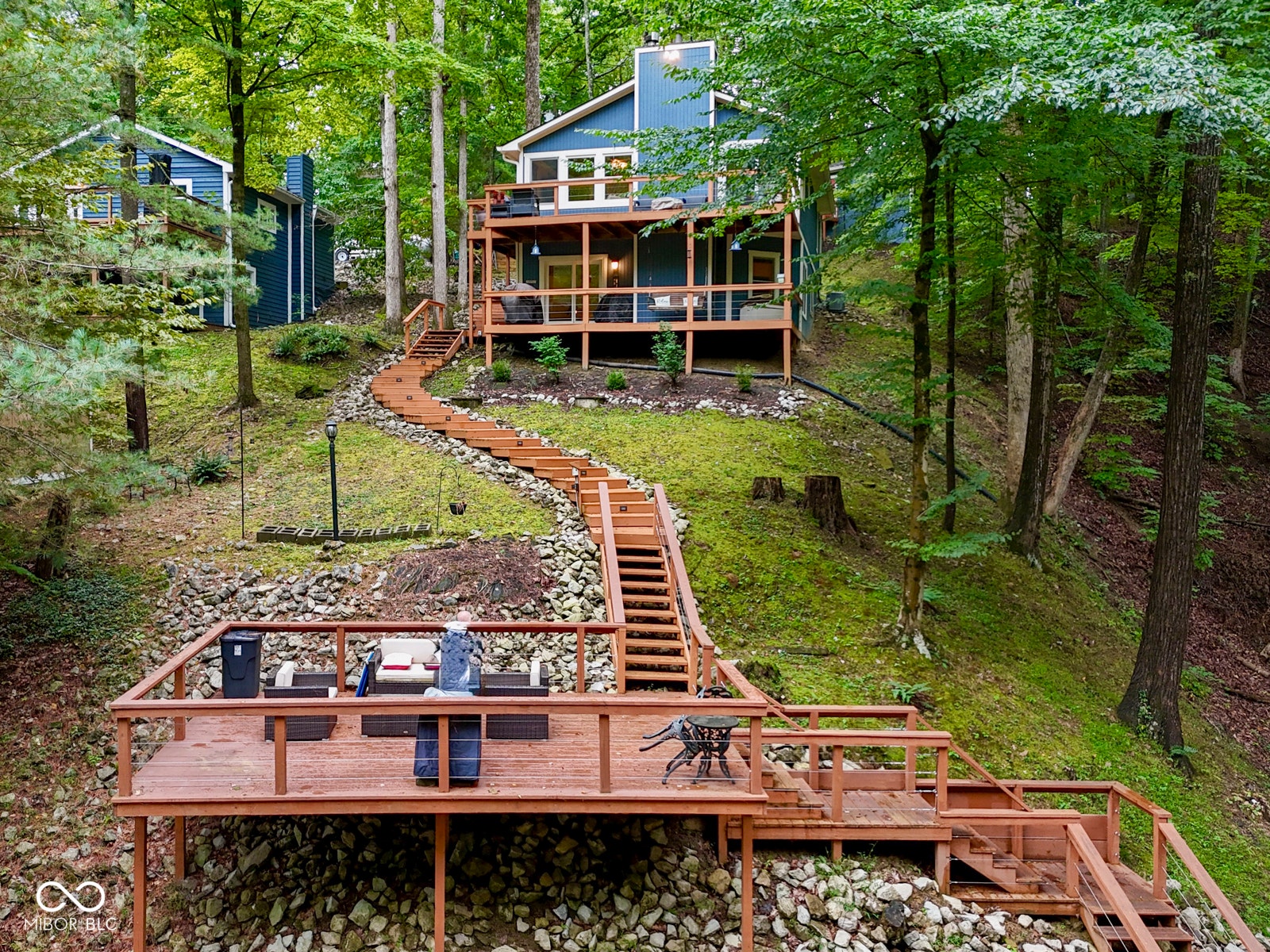 Multi-level property with expansive outdoor decking, multiple balconies, and a long wooden staircase providing access to each level