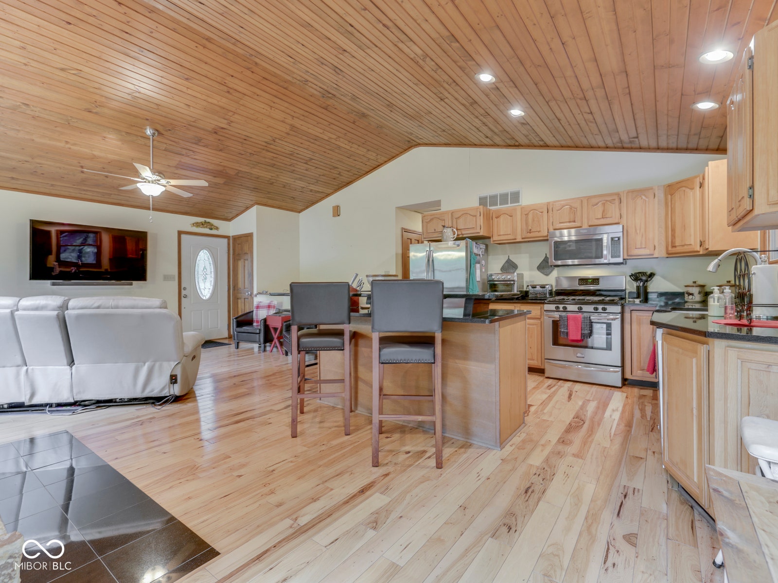 Wood-finish vaulted ceiling with recessed lighting, light wood-finish flooring, and a kitchen island with seating