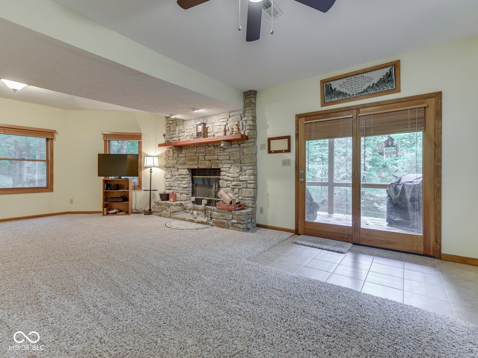 Stone fireplace with a wood mantle, wood-framed windows, and wood-framed sliding glass doors