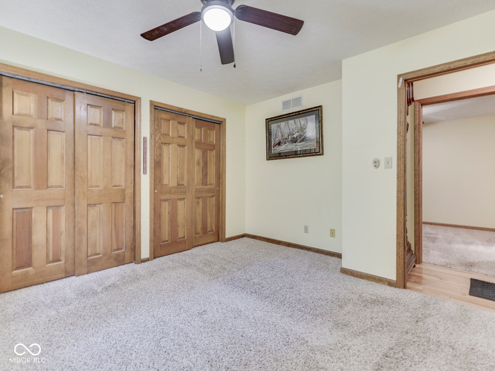 Recessed ceiling fan with integrated lighting, wood-finish bi-fold closet doors, light-toned carpeting, and wood-finish door frames
