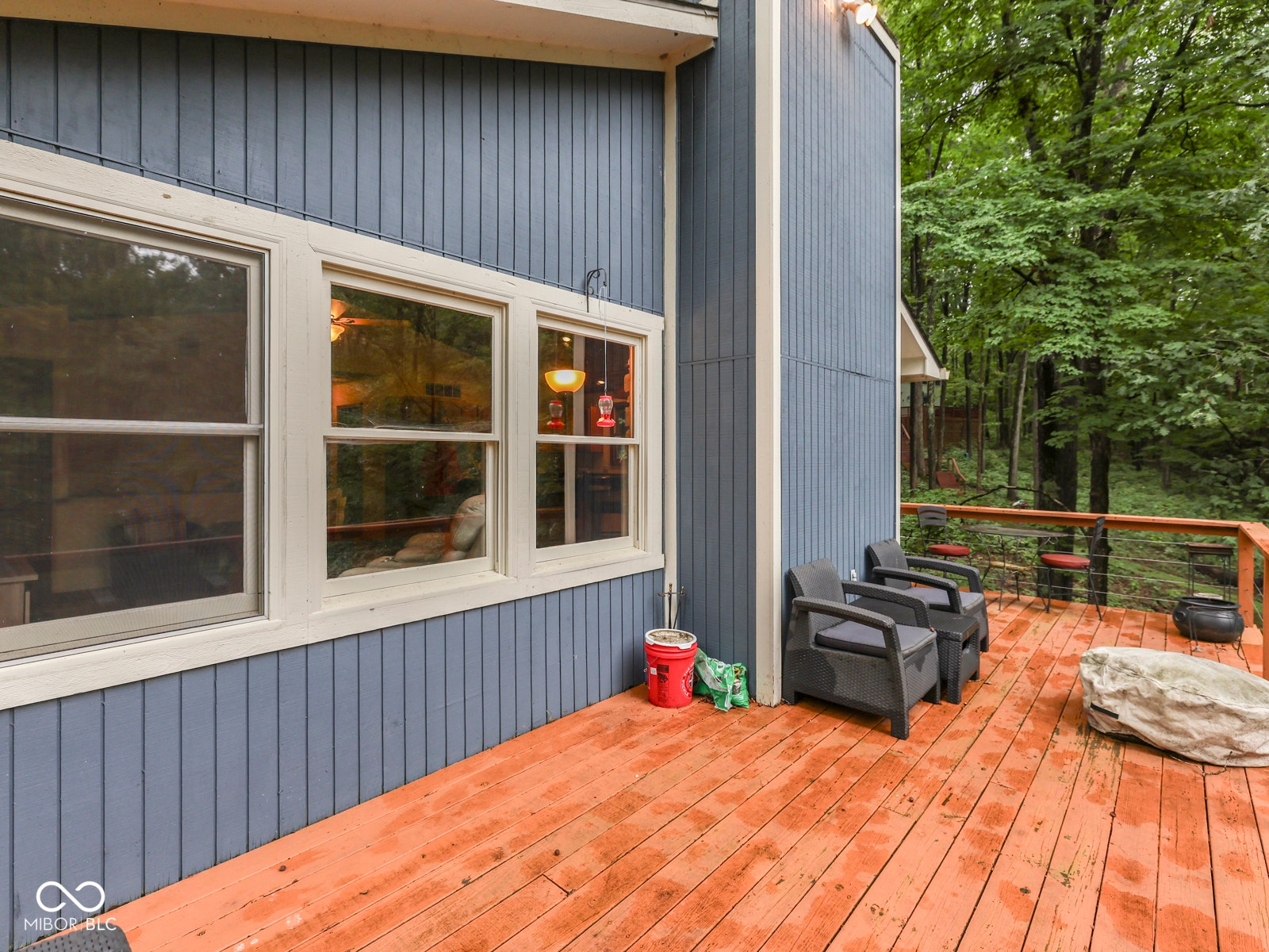 Wood deck with a natural wood finish, featuring light blue siding and multiple windows with white trim