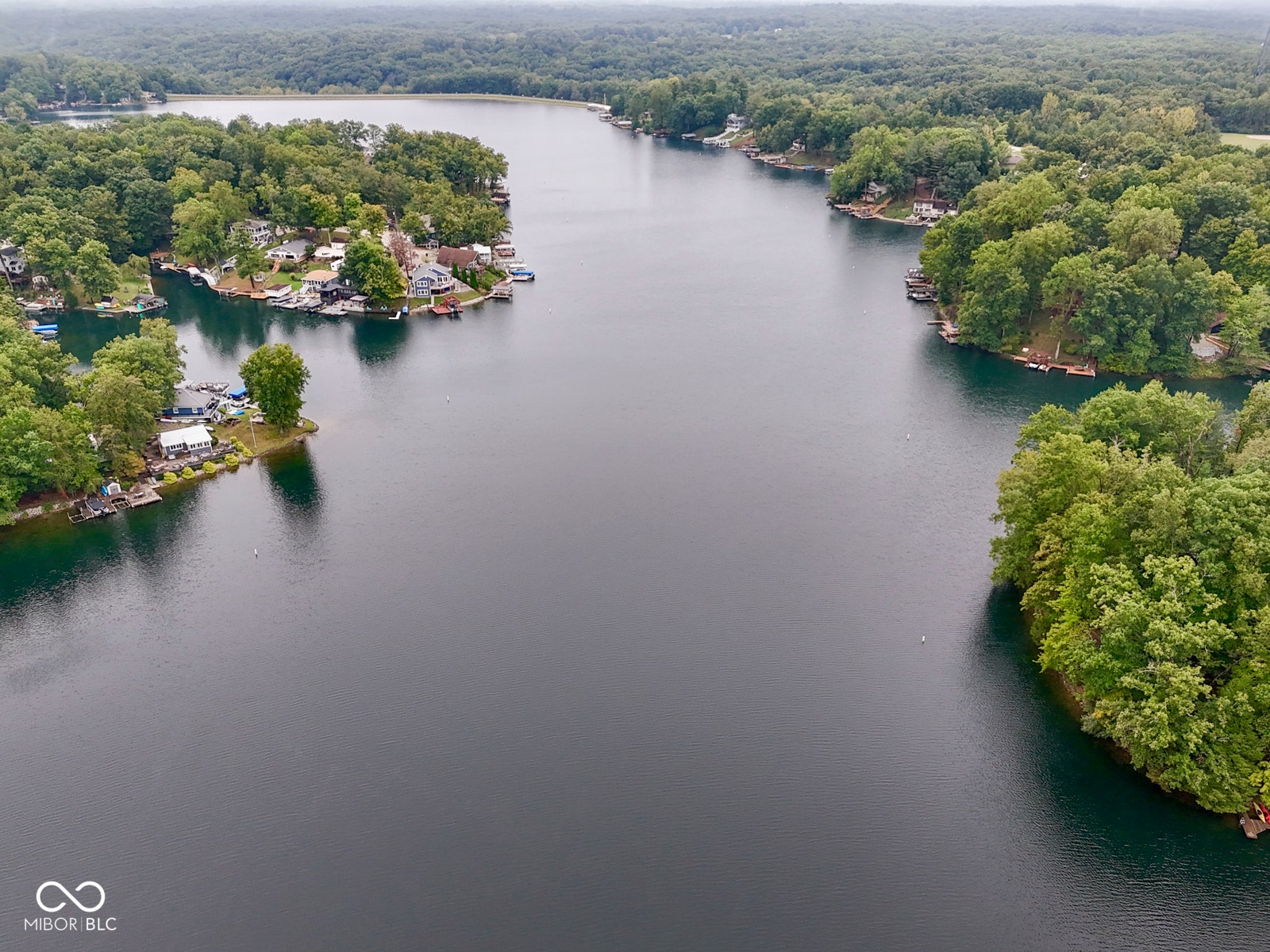 Expansive lake with wooded shores, featuring multiple waterfront properties and private docks