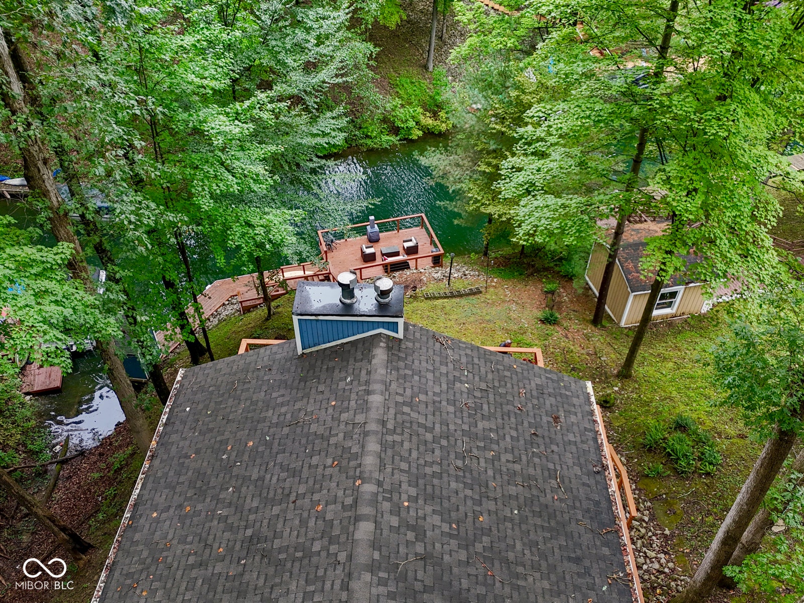 Gable roof with asphalt shingles, blue siding, a private dock with a raised platform, and a detached shed