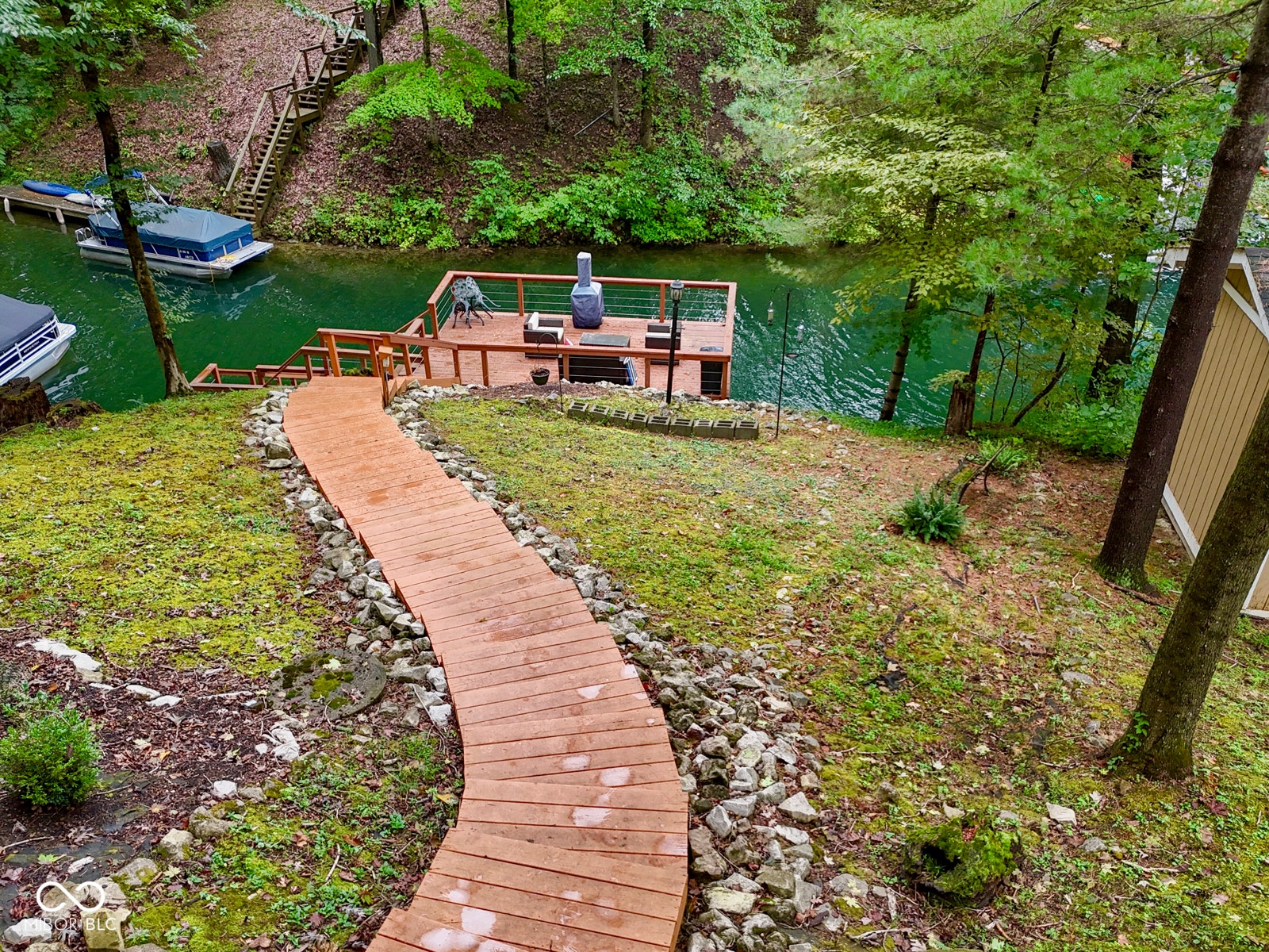 Wood pathway leading to a waterfront dock with a built-in outdoor fireplace