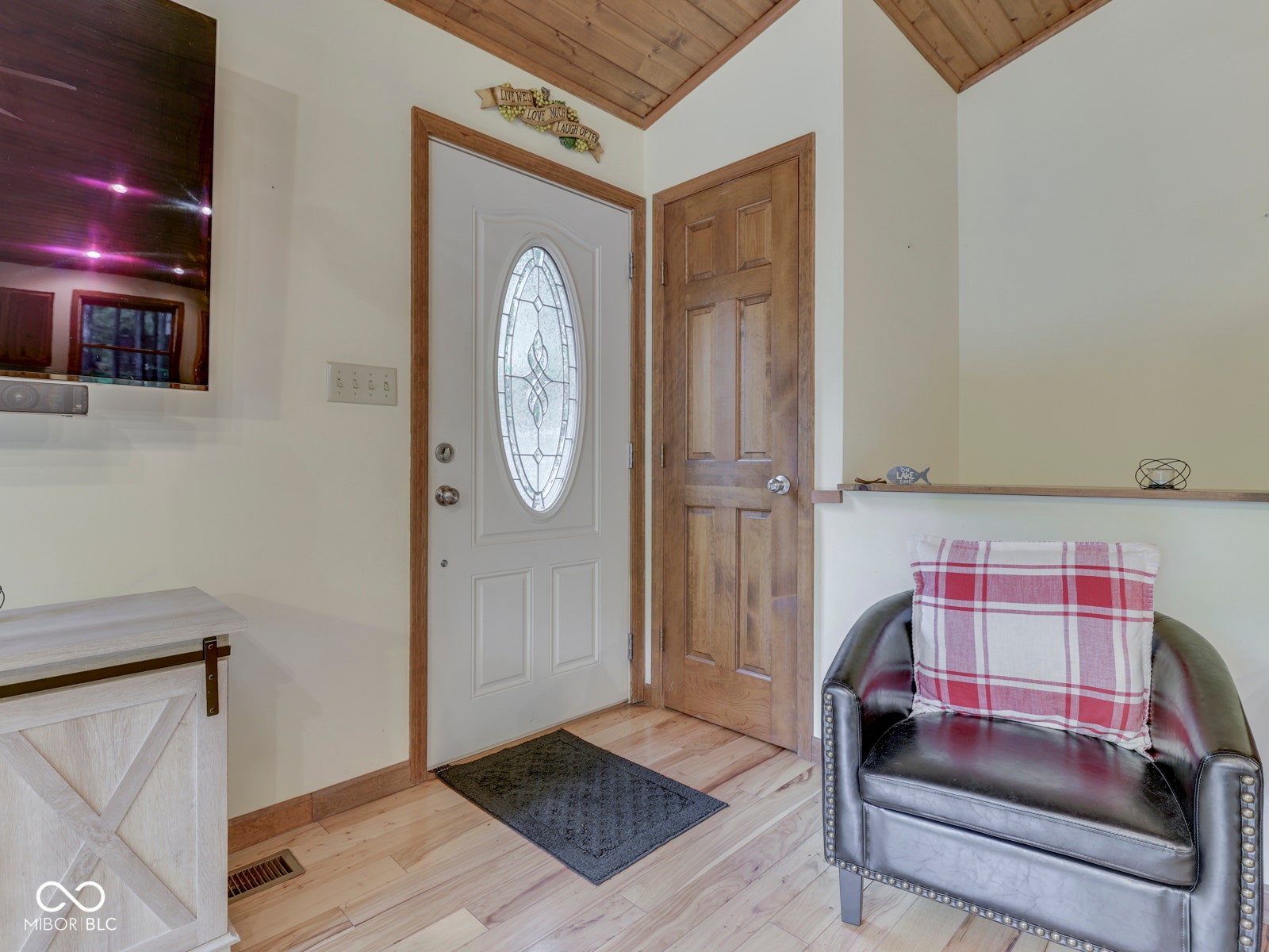 Entryway featuring a white door with an oval leaded glass insert, a solid wood door, and wood-finish flooring