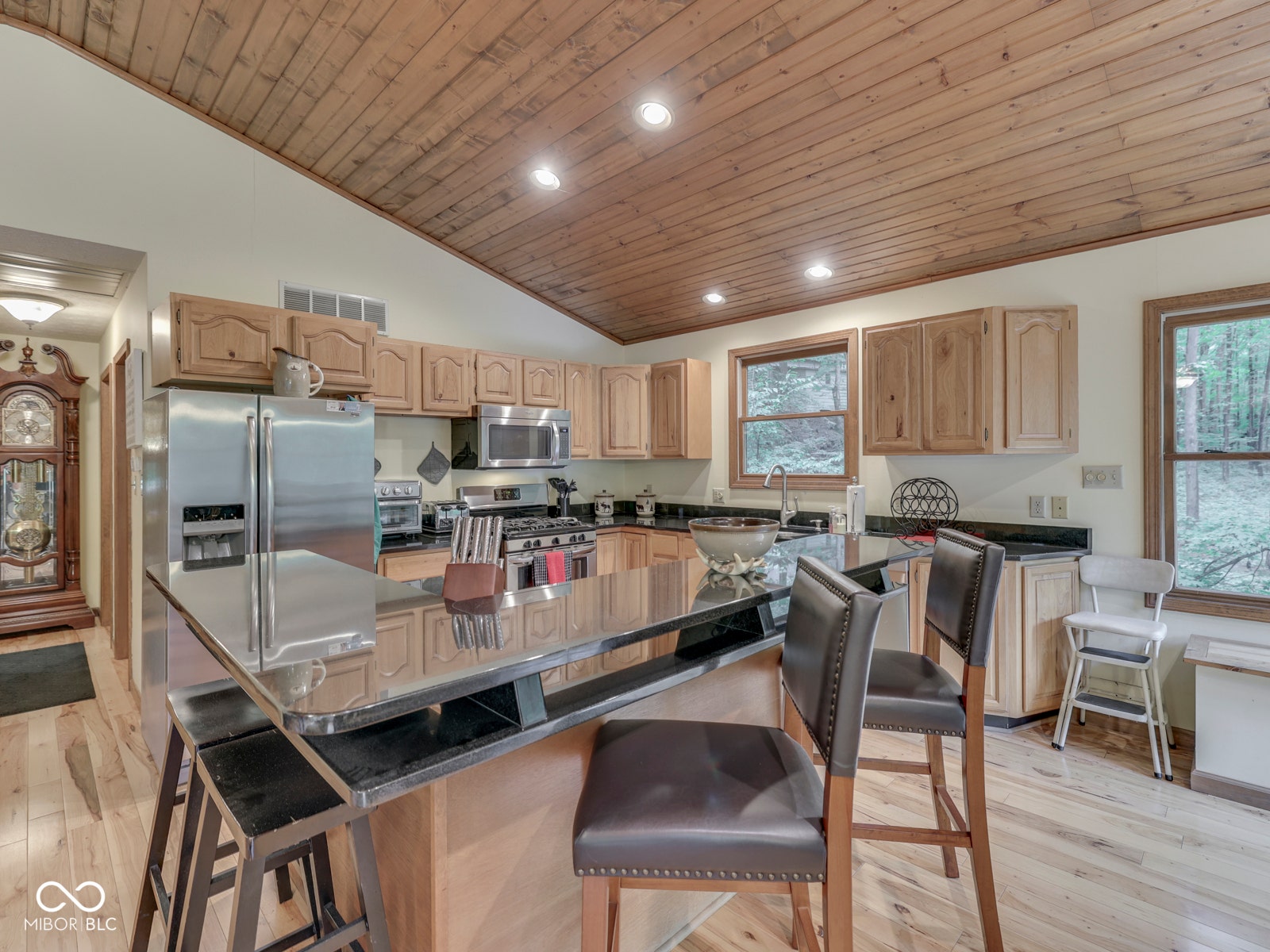 Kitchen with wood-finish flooring, natural wood cabinetry, stainless steel appliances, and a central island with bar seating