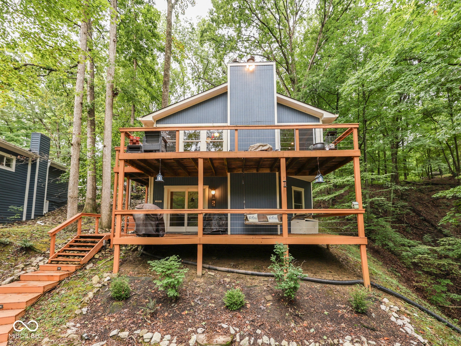 Two-story deck with wood railings, gray siding, and multiple outdoor light fixtures